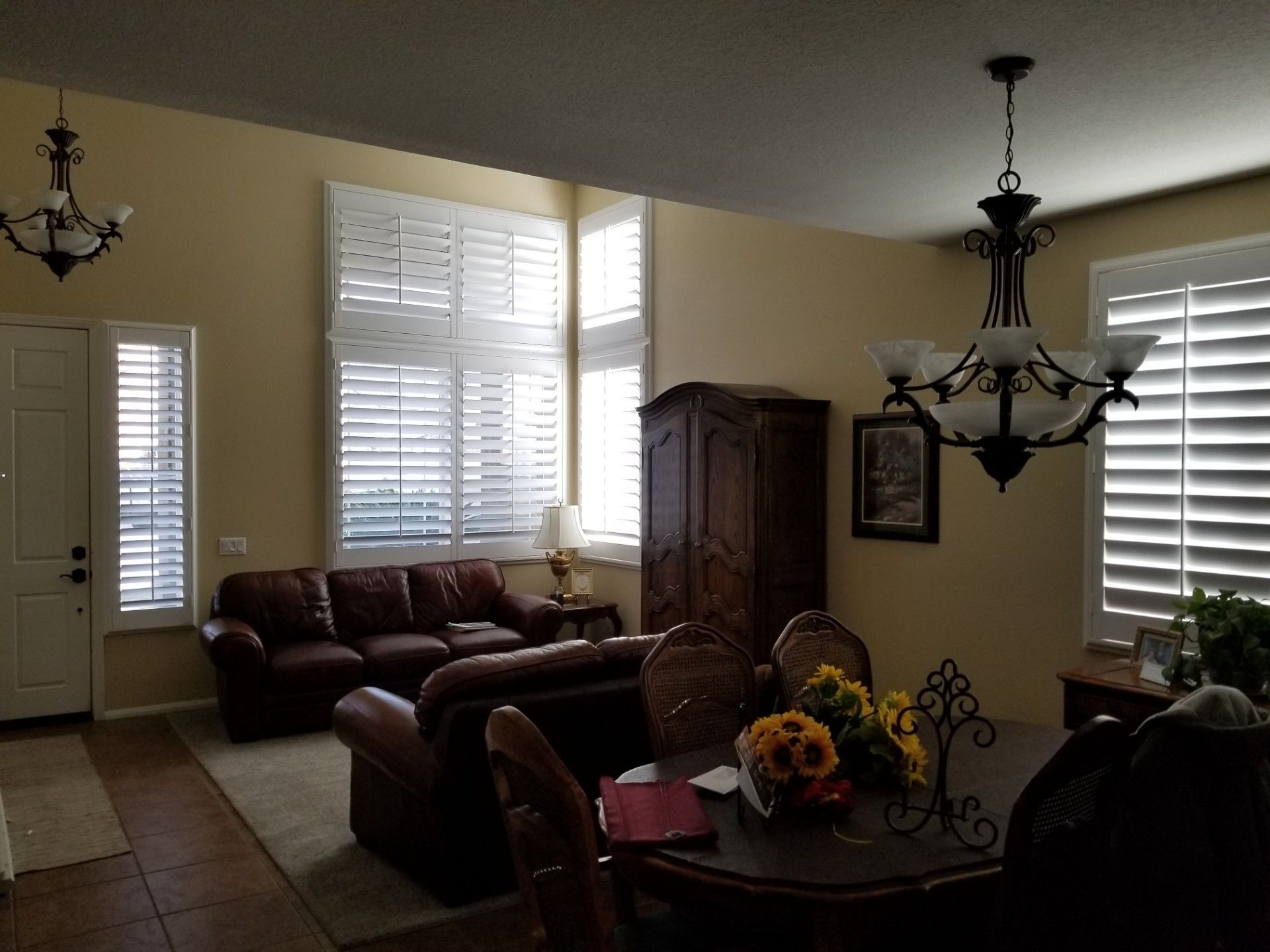Living room with brown leather furniture, wooden table, and shutters.