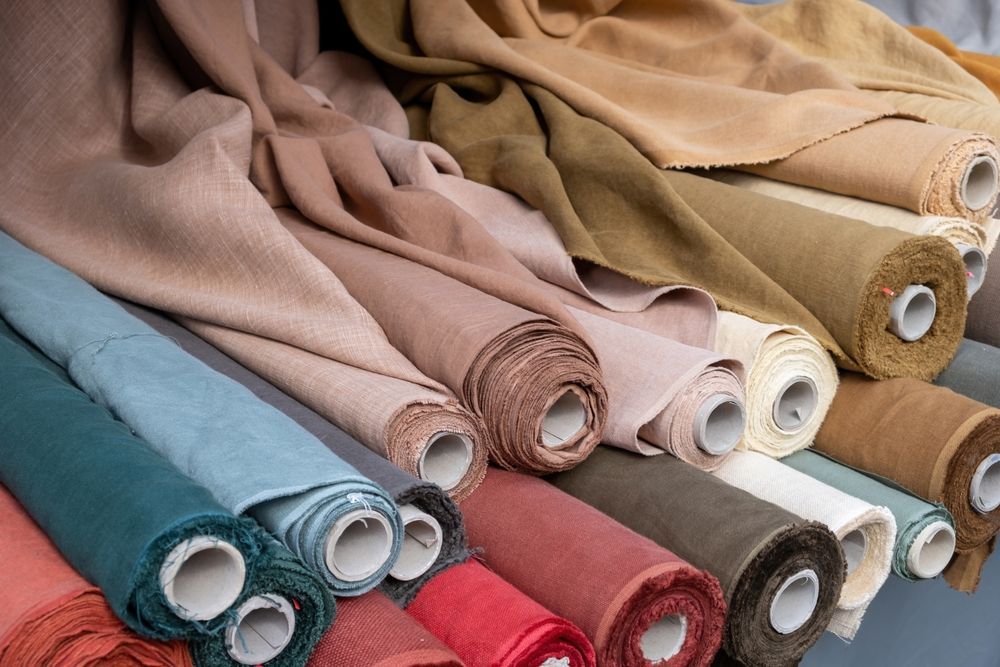 Rolls of various colored fabric, including beige, blue, and red.