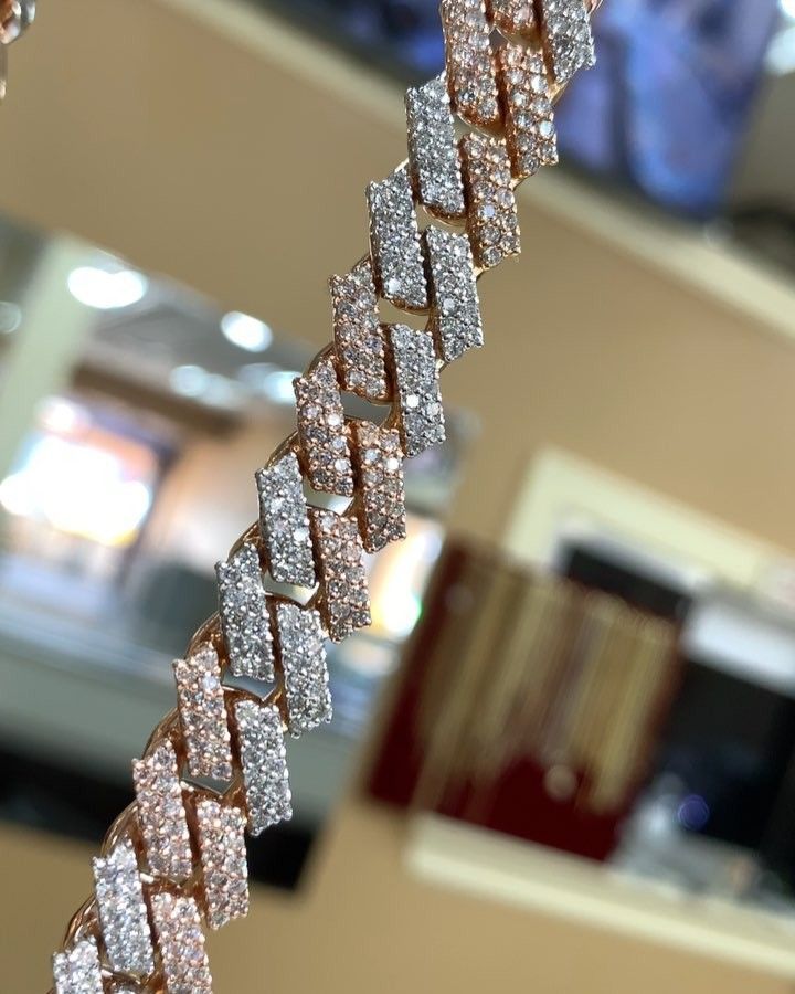 Close-up of a glittering zigzag silver bracelet hanging indoors, with a blurred retail background