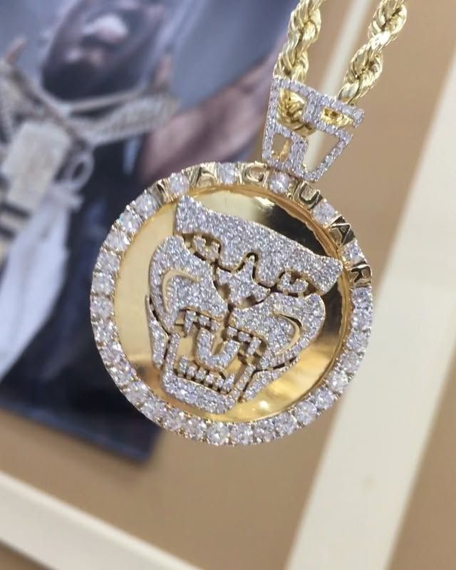 Gold and diamond pendant necklace with a circular medallion and crown design hanging on a display card