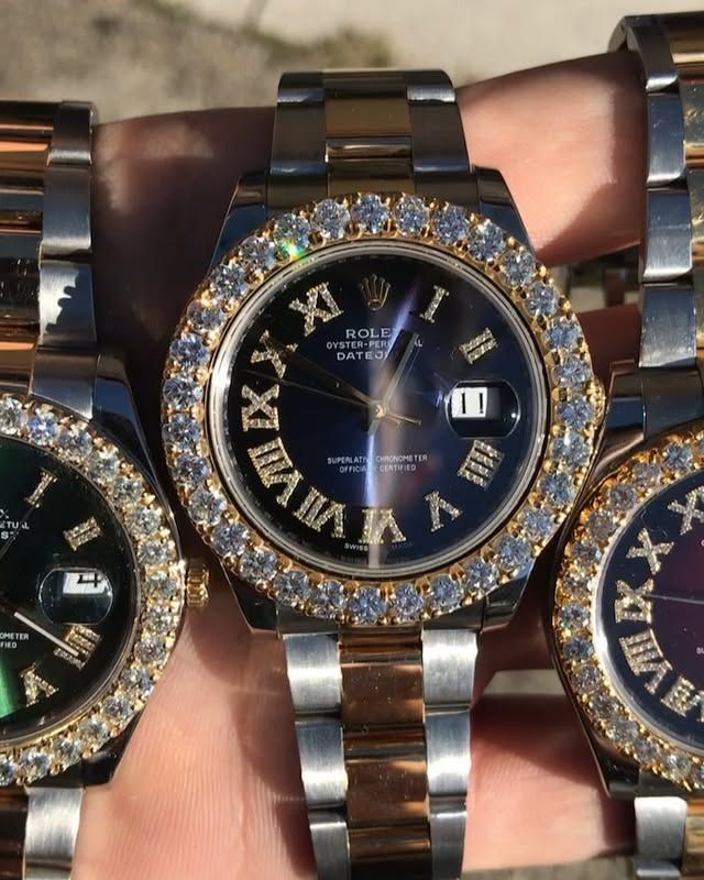 Three jeweled wristwatches with black faces and gold bracelets stacked on a hand