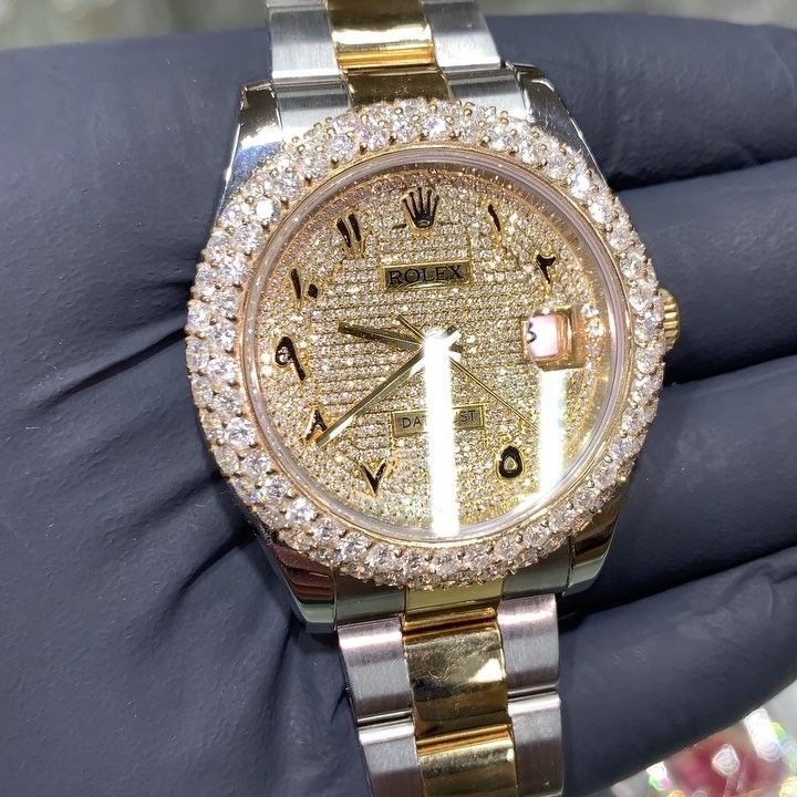 Gold and diamond Rolex watch with two-tone band, held in a gloved hand