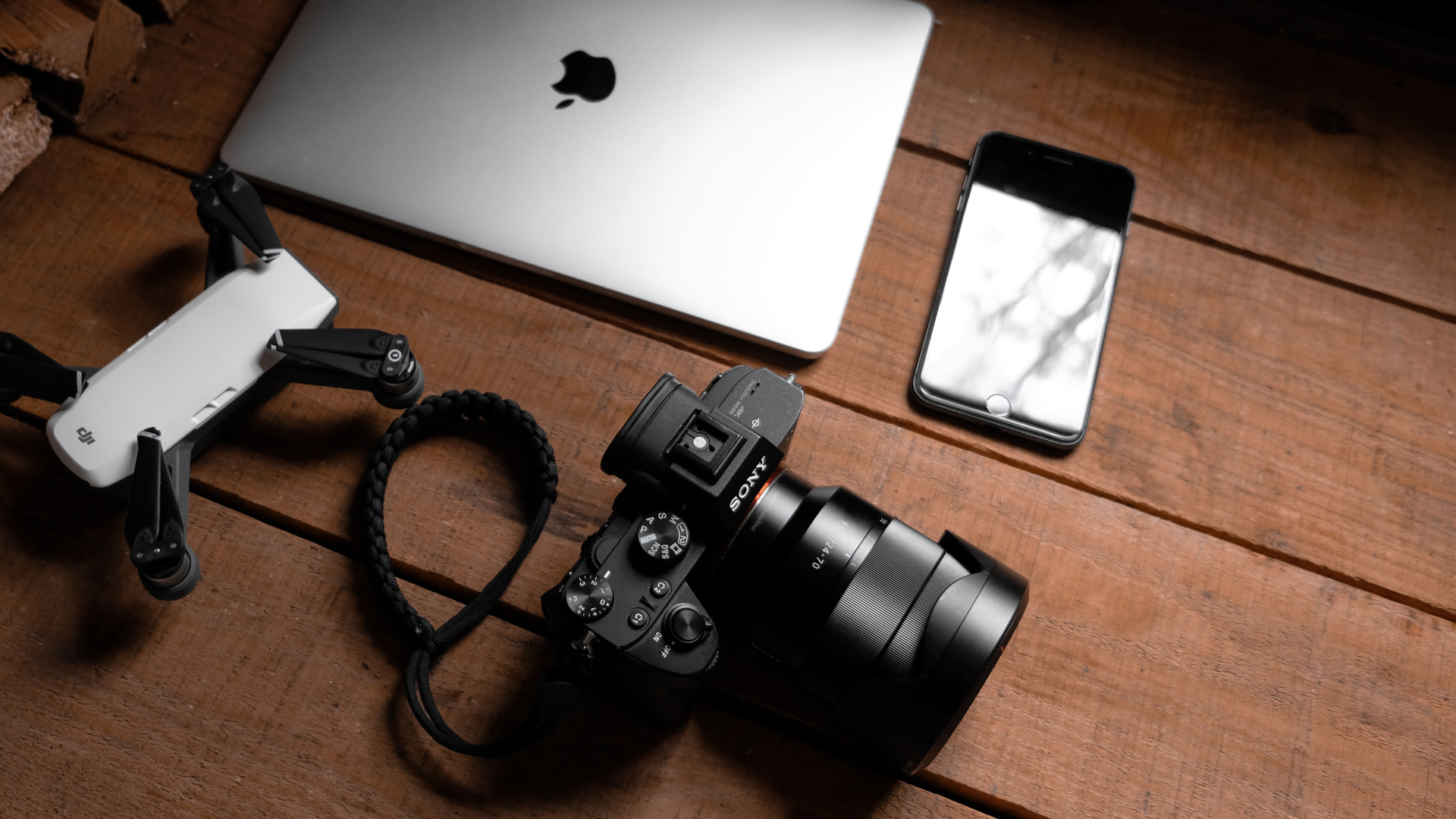 Assorted electronics and gadgets on a desk, including a tablet, headphones, keyboard, and camera gear.