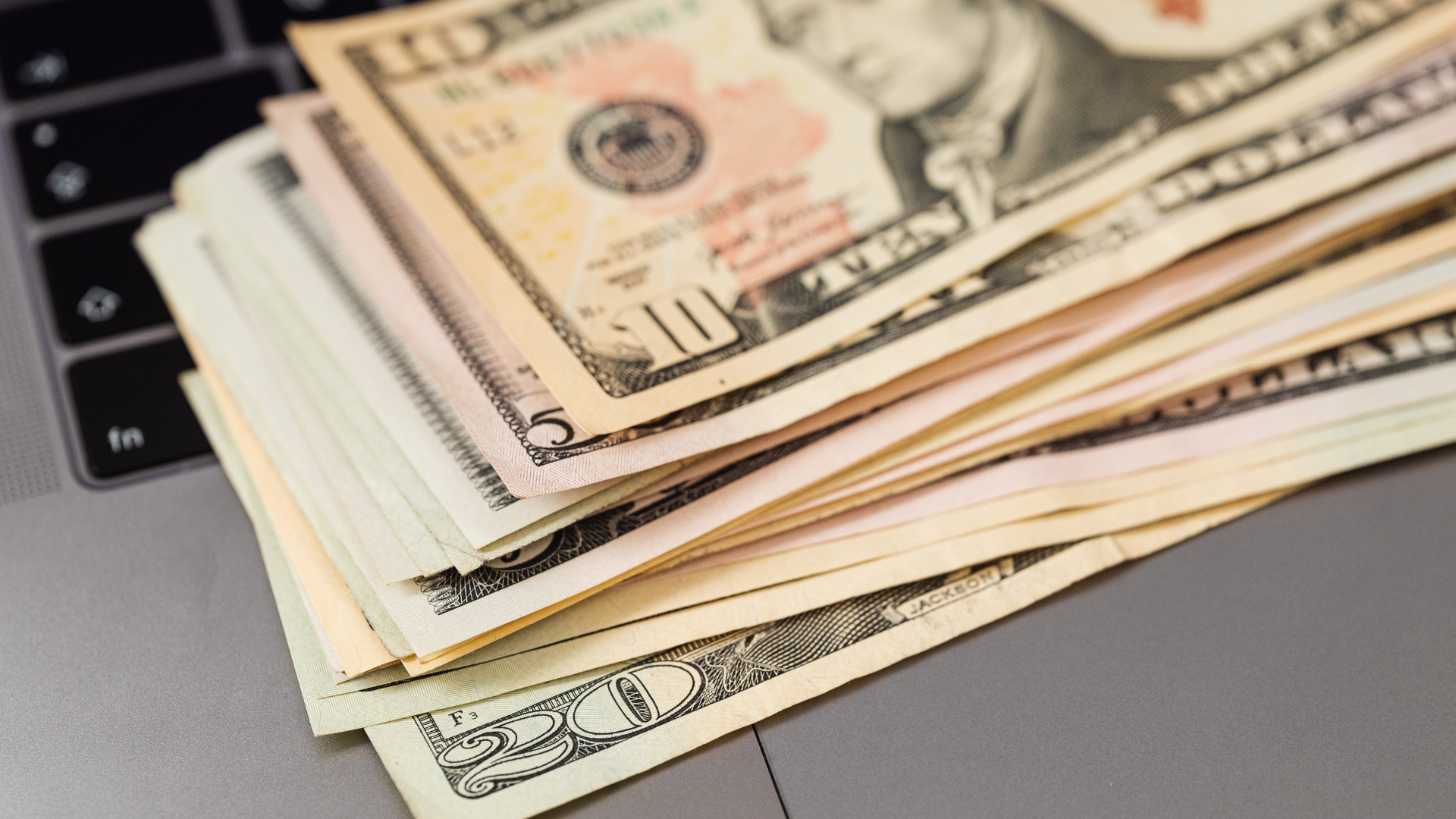 Hands exchanging cash bills over a dark table with scissors in the background