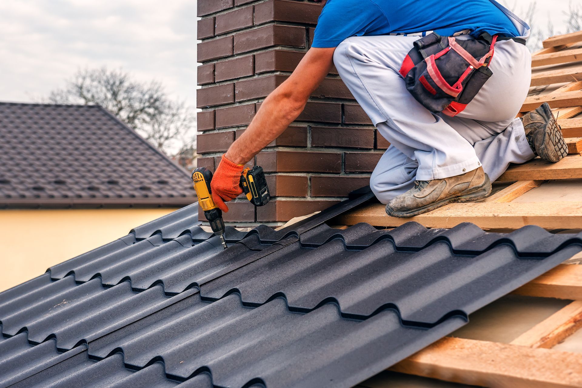 Professional roofing services contractor installing metal roof tiles on a residential home. Professional roofing services contractor installing metal roof tiles on a residential home.