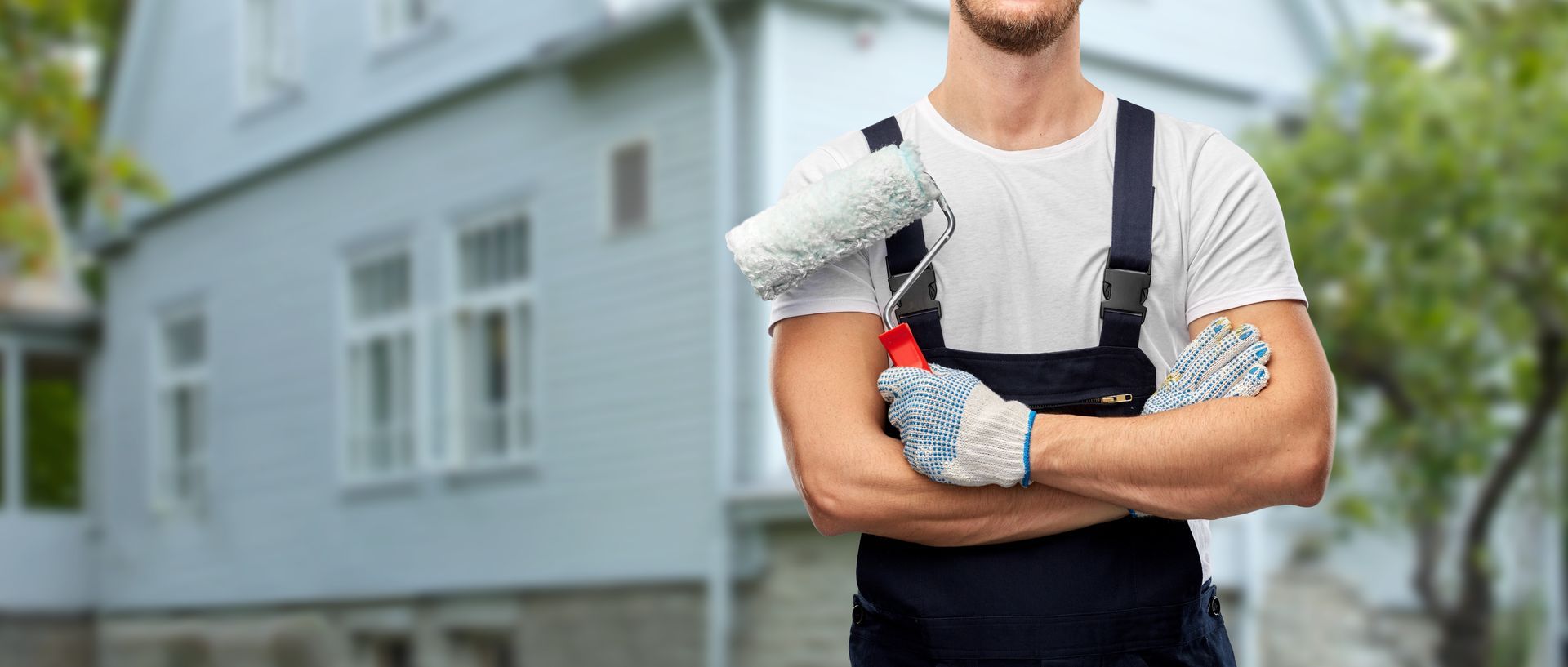Close up of painter or builder with paint roller over living house