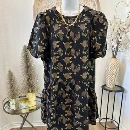 A black dress with gold flowers on it is on a mannequin.