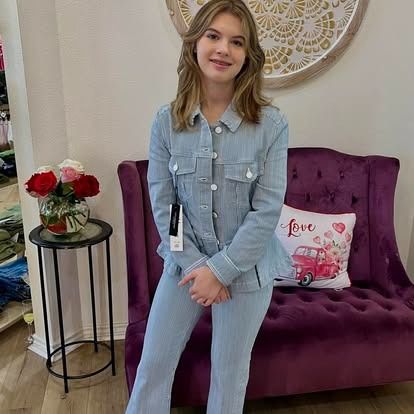 A young woman is standing next to a purple couch in a room.