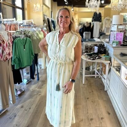 A woman in a white dress is standing in a clothing store.