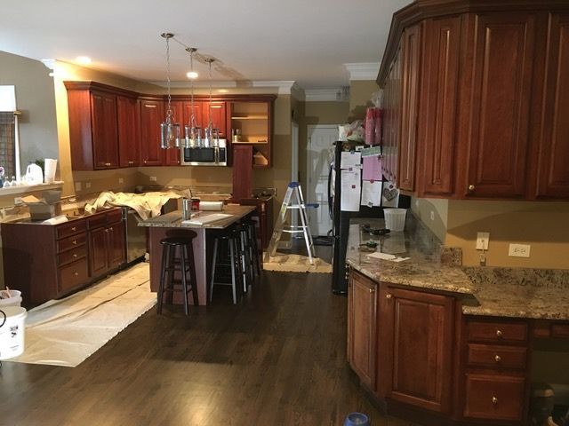 Kitchen with reddish-brown cabinets, countertops, and an island under construction. A ladder is present.