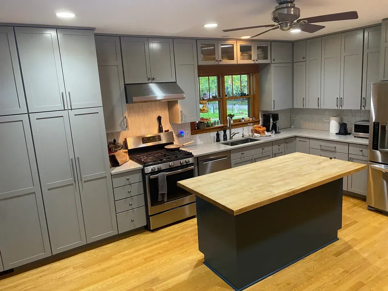 Gray kitchen with stainless steel appliances, butcher block island, and light wood flooring.