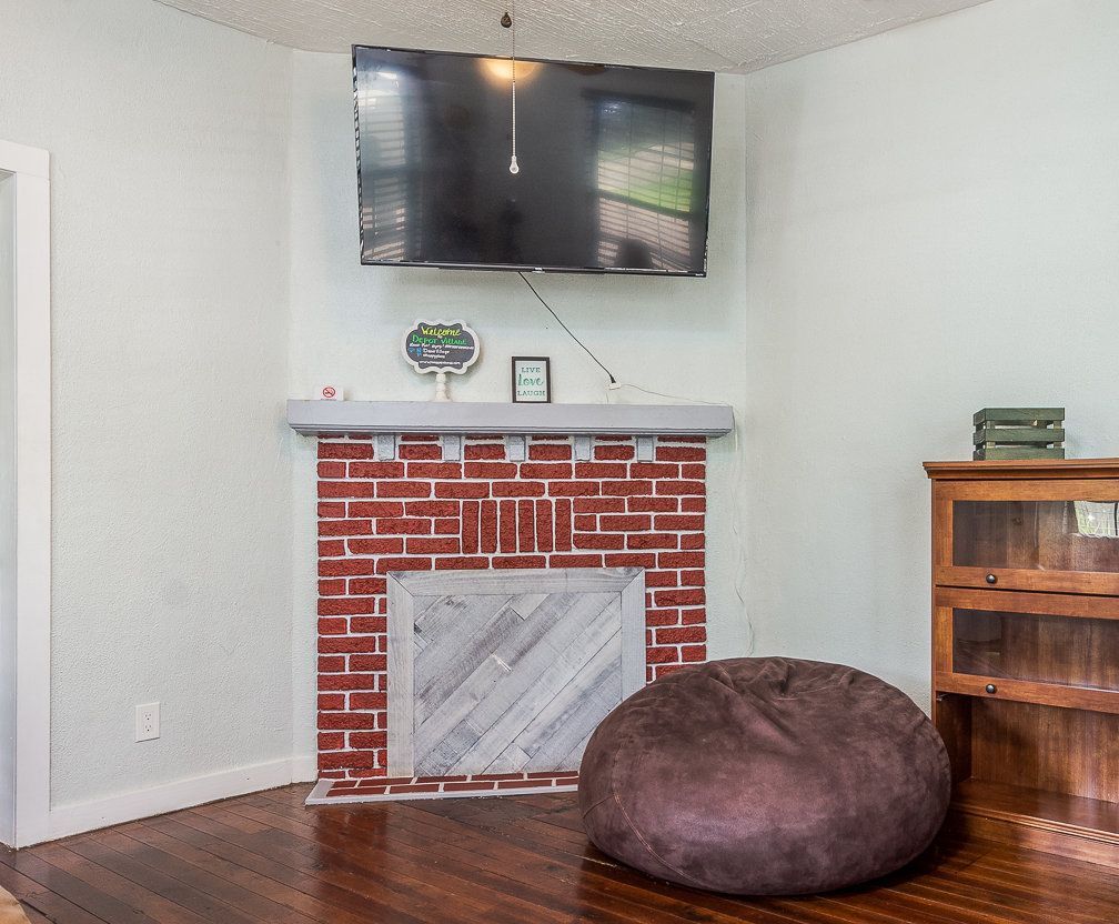 Living room with brick fireplace, TV, beanbag chair, and wooden bookcase.