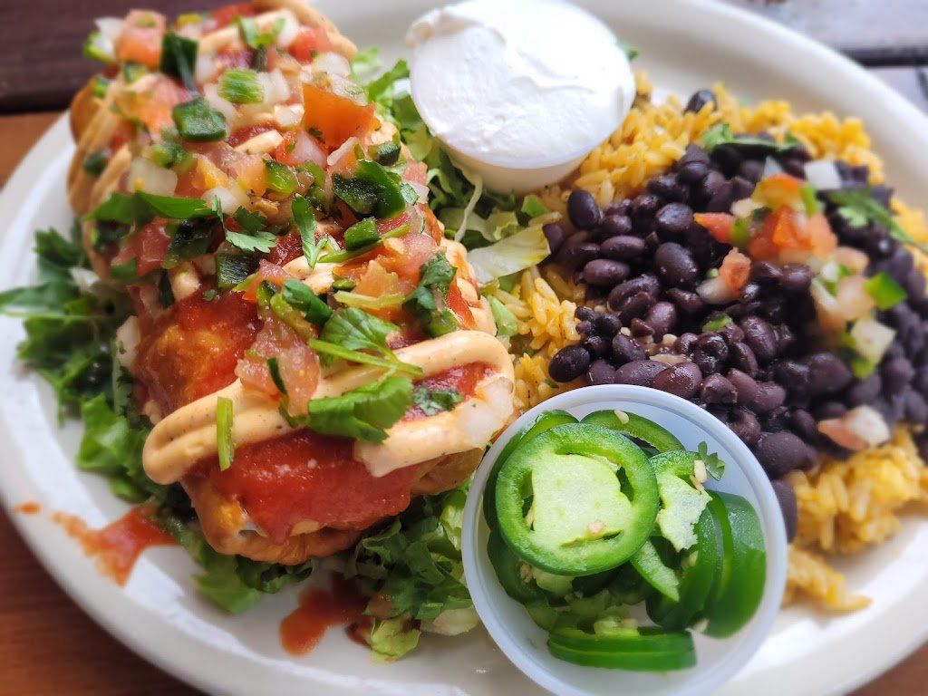 Plate of Mexican food: fried burritos with salsa, rice, beans, sour cream, and jalapeños.