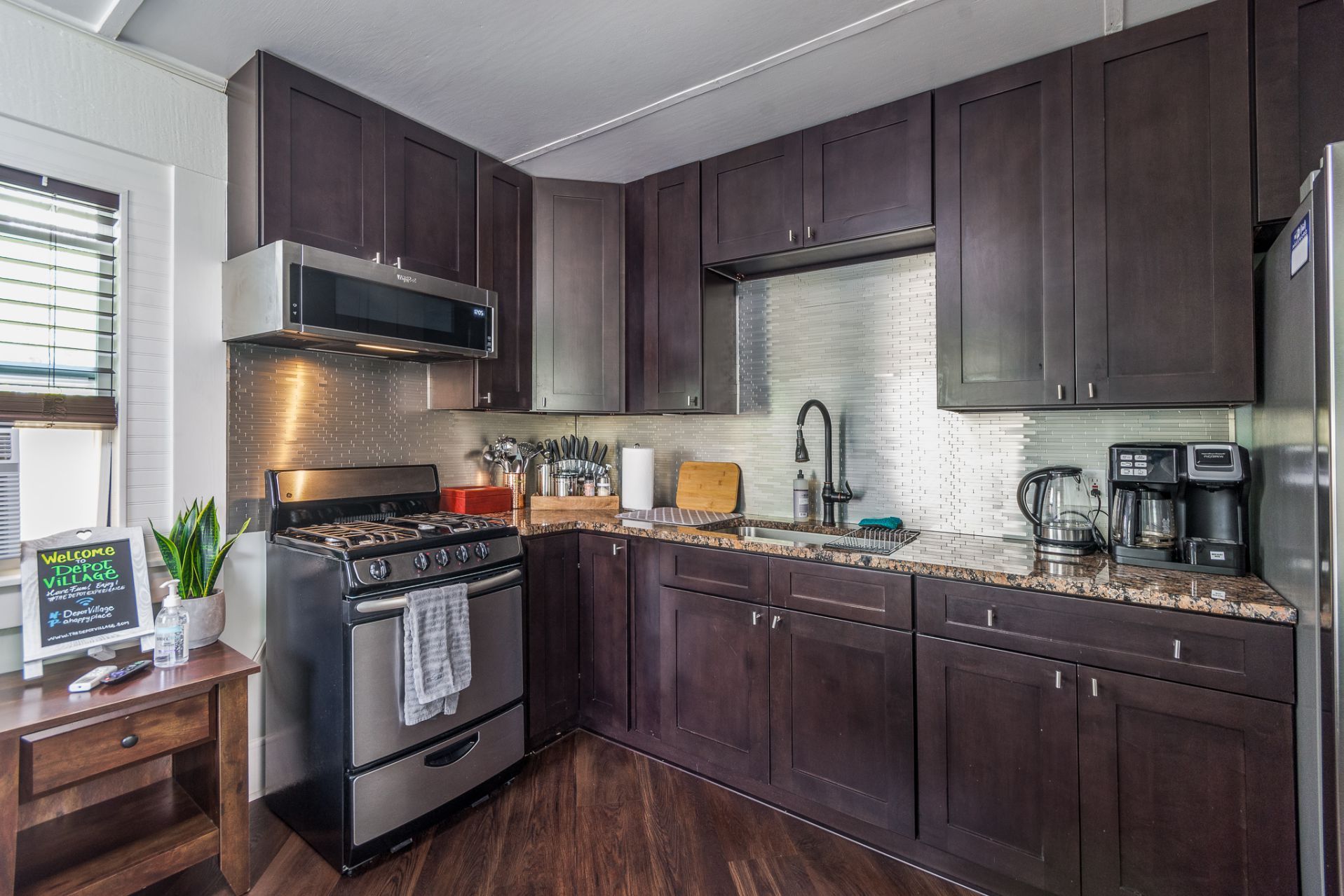 Dark wood kitchen with stainless steel appliances and countertops.