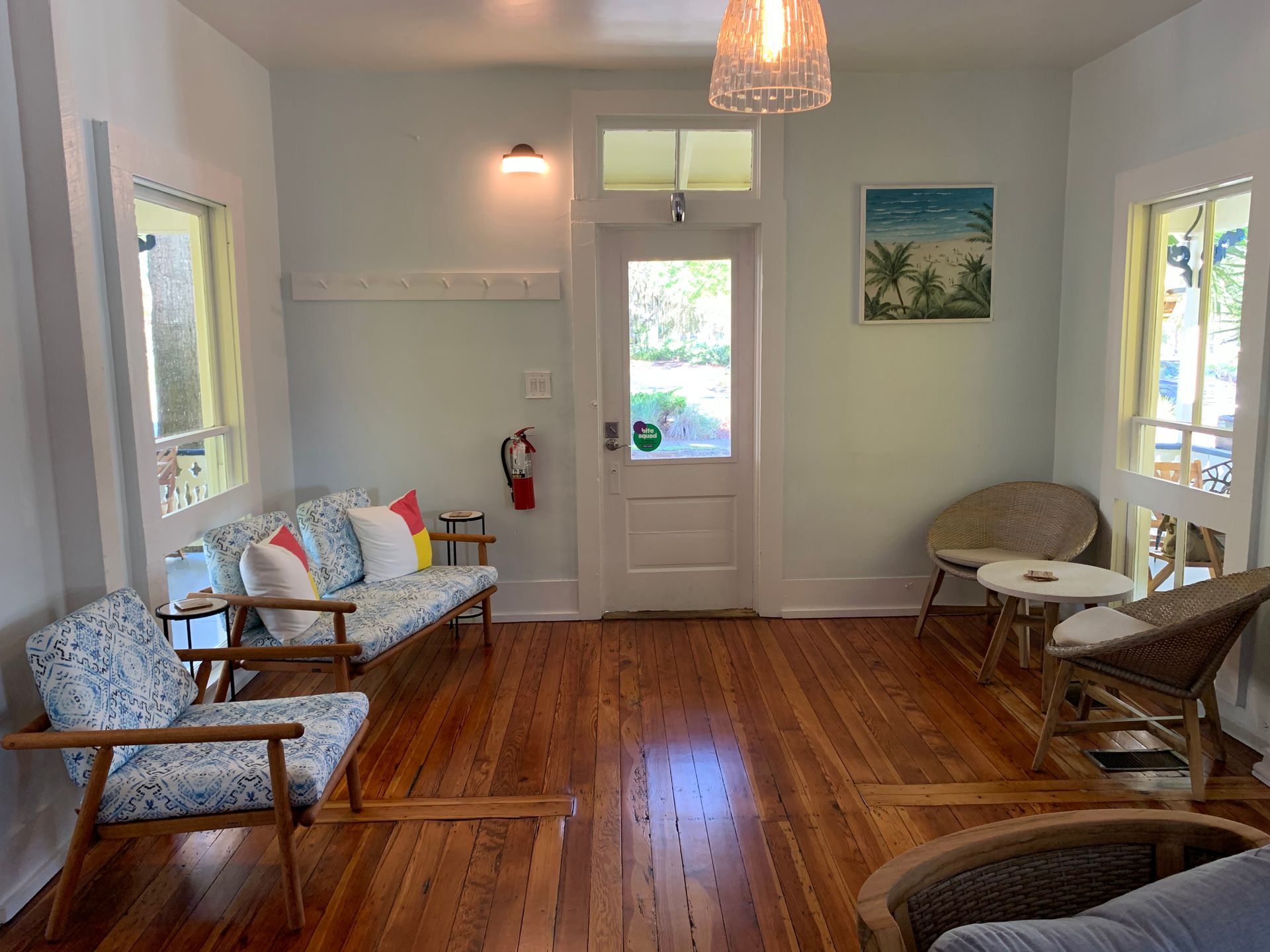 Room with wooden floors, light blue walls, seating, and a door leading outside.