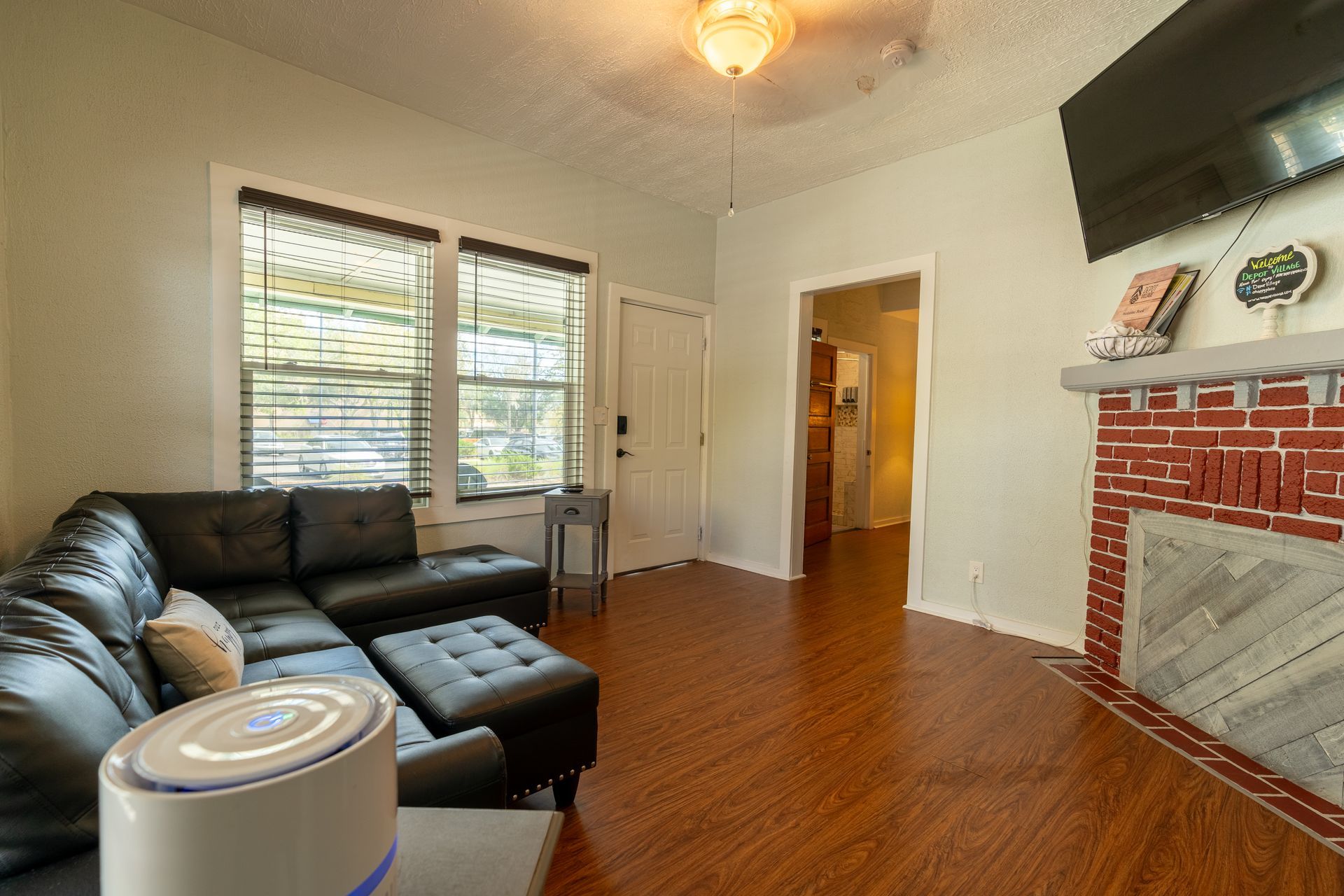 Living room with dark gray sectional sofa, brick fireplace, and wood-look flooring.