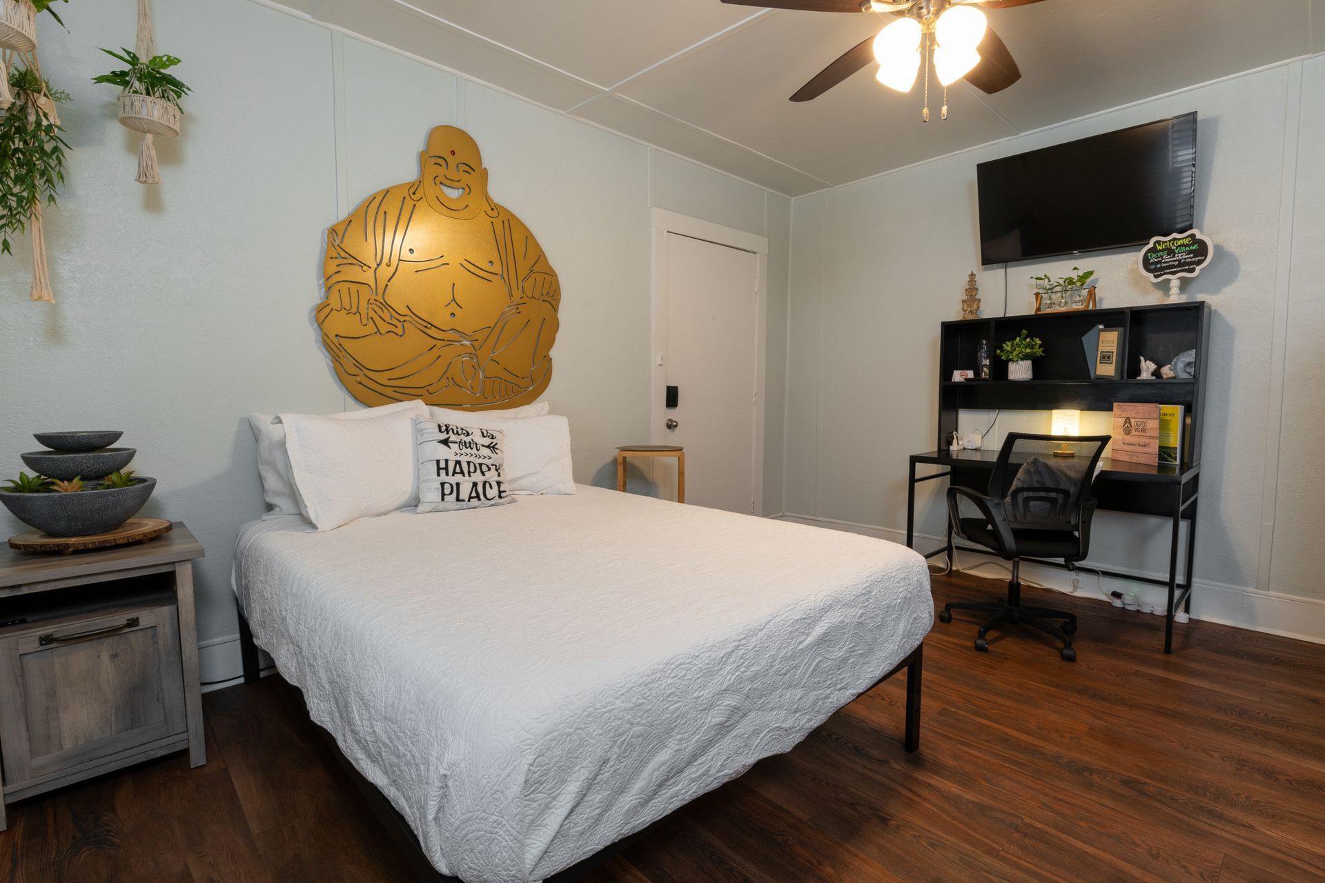 Bedroom with bed, desk, artwork, TV, and ceiling fan. Wooden floors, light blue walls.
