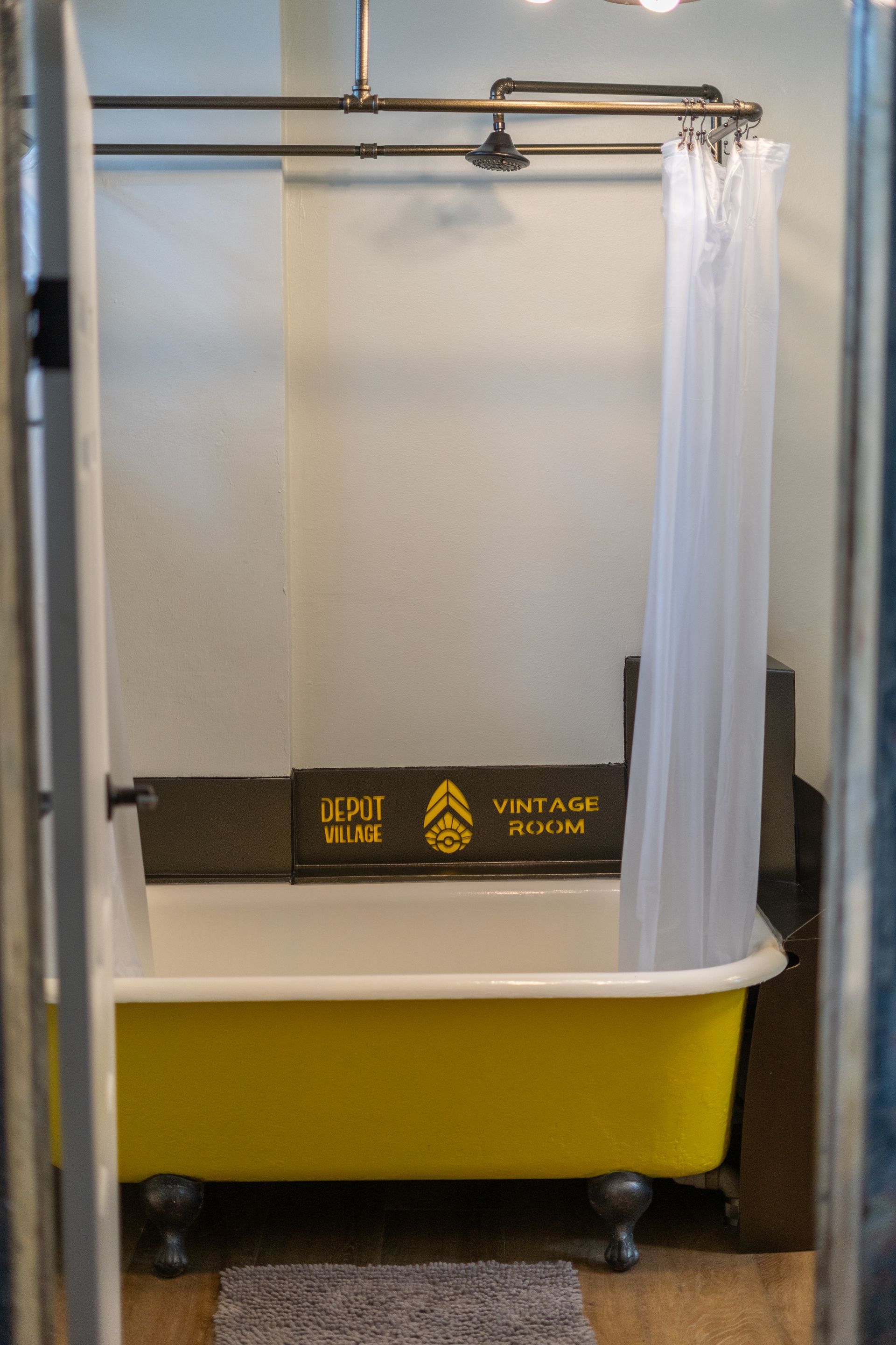 Yellow clawfoot bathtub, shower curtain, and shower rod in a vintage-style bathroom.