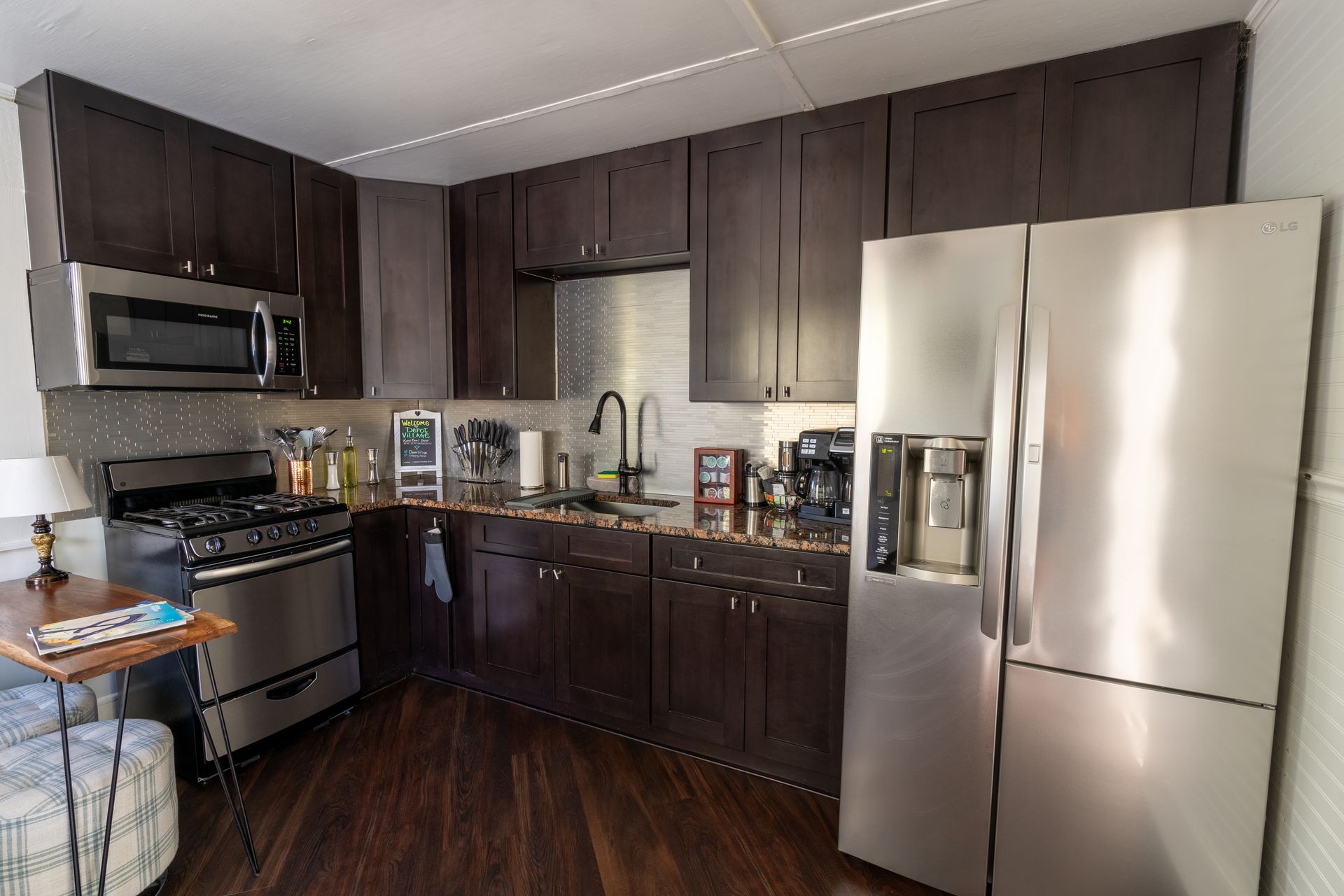 Small kitchen with dark cabinets, stainless steel appliances, and dark wood floors.