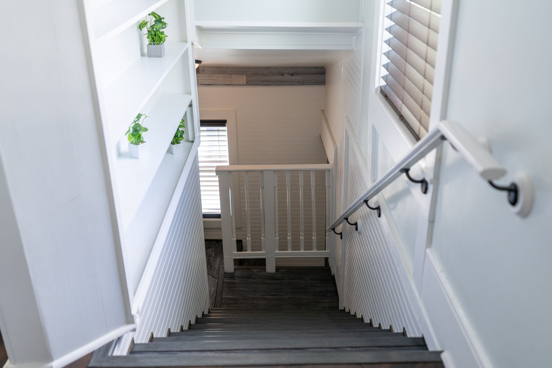 White stairwell with railing and potted plants leading to guest rooms