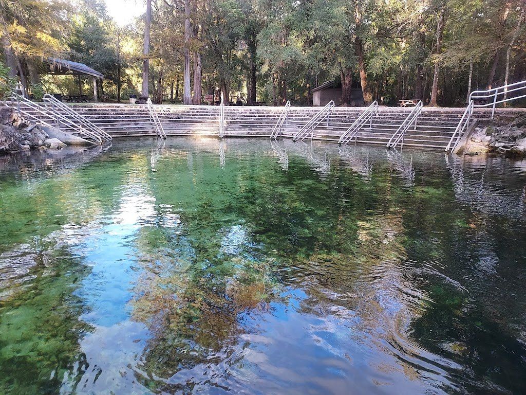 Clear spring water with concrete steps and railings for access. Trees frame the scene.