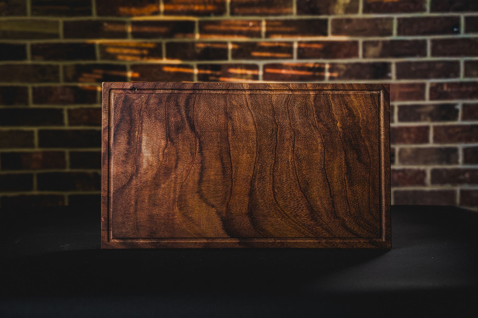 Tablas de cortar de madera envueltas con embalaje marrón y cordel, apiladas sobre una superficie de madera.