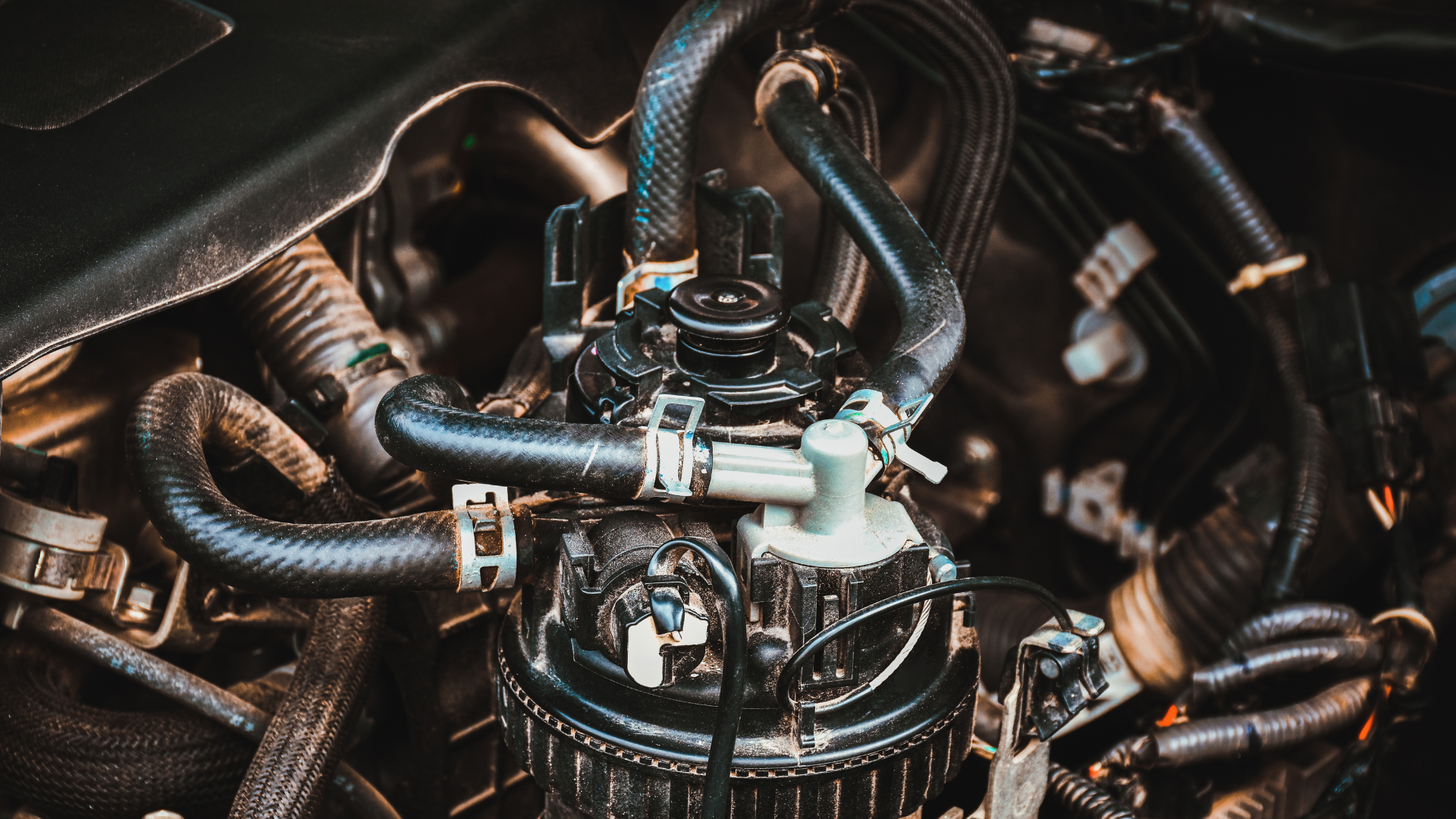 Close-up of a tangled mechanical engine with black hoses and metal components