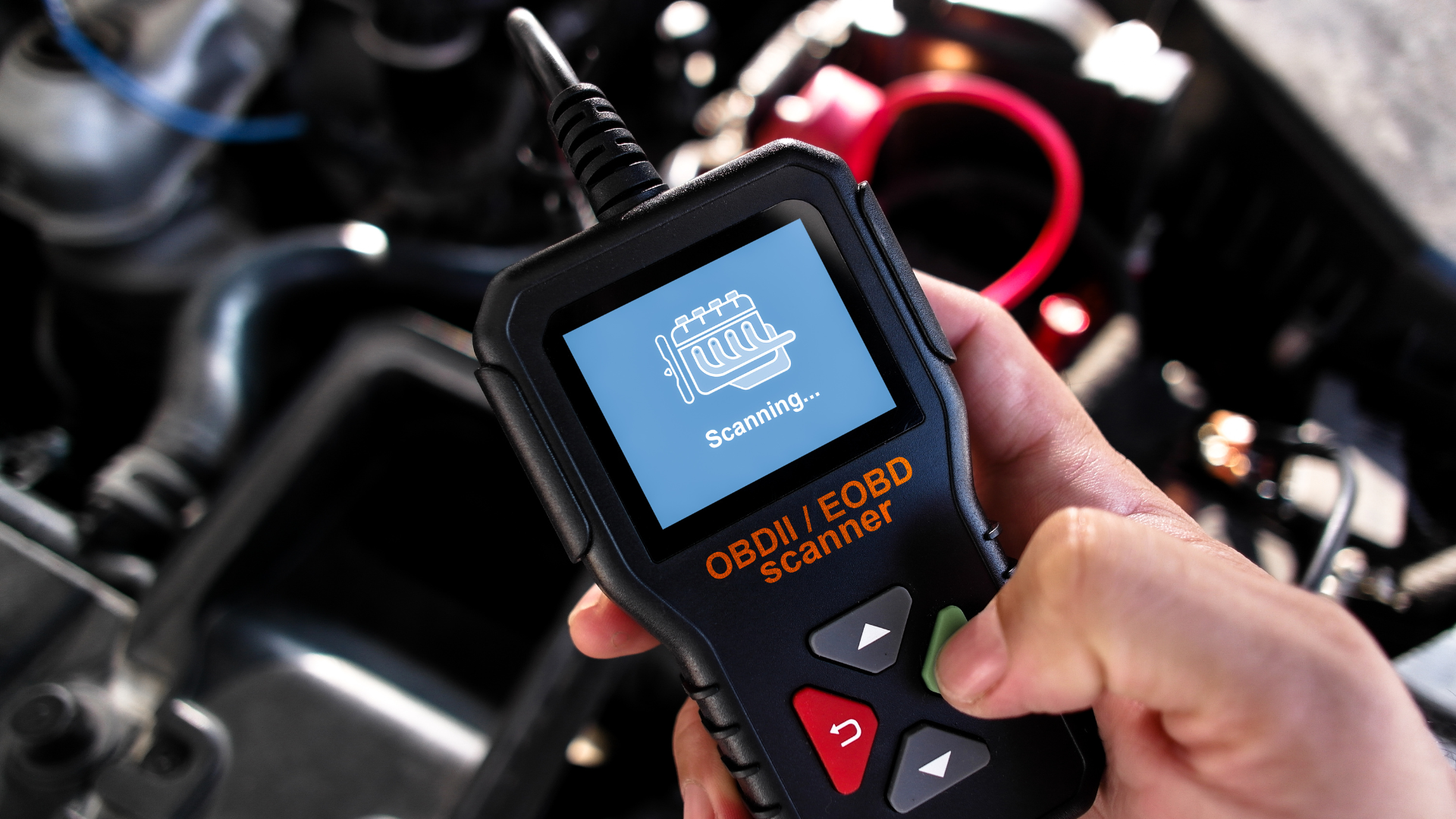Hand holding an automotive diagnostic scanner with error code display in an engine bay