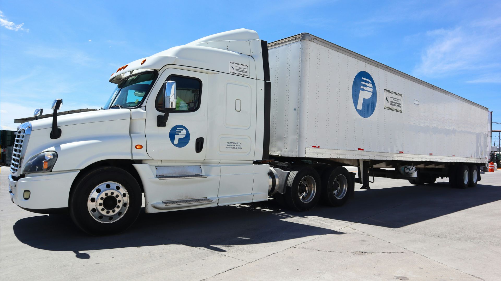 White semi-truck with trailer parked outdoors on a sunny day.