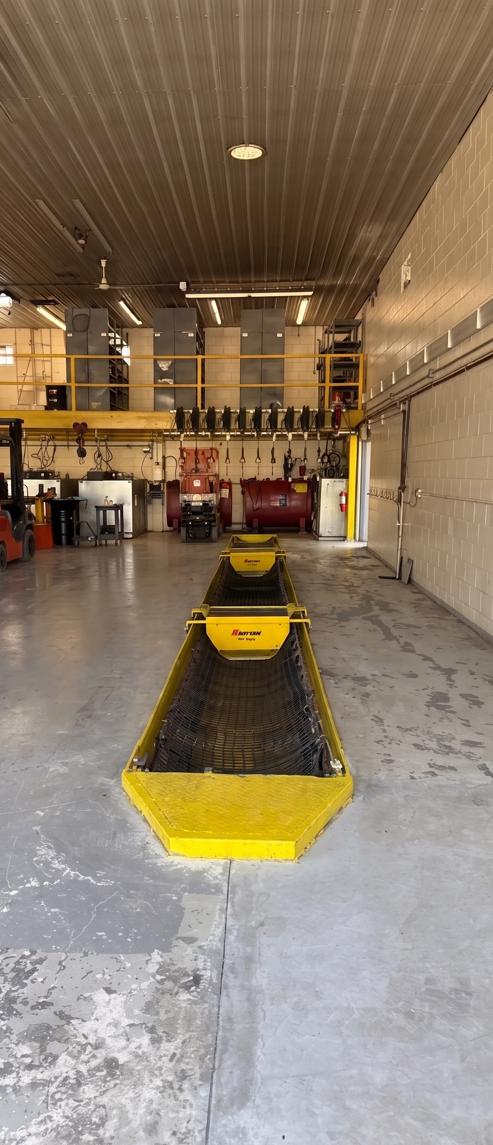 Yellow industrial cart in a warehouse aisle, with storage racks and equipment in the background
