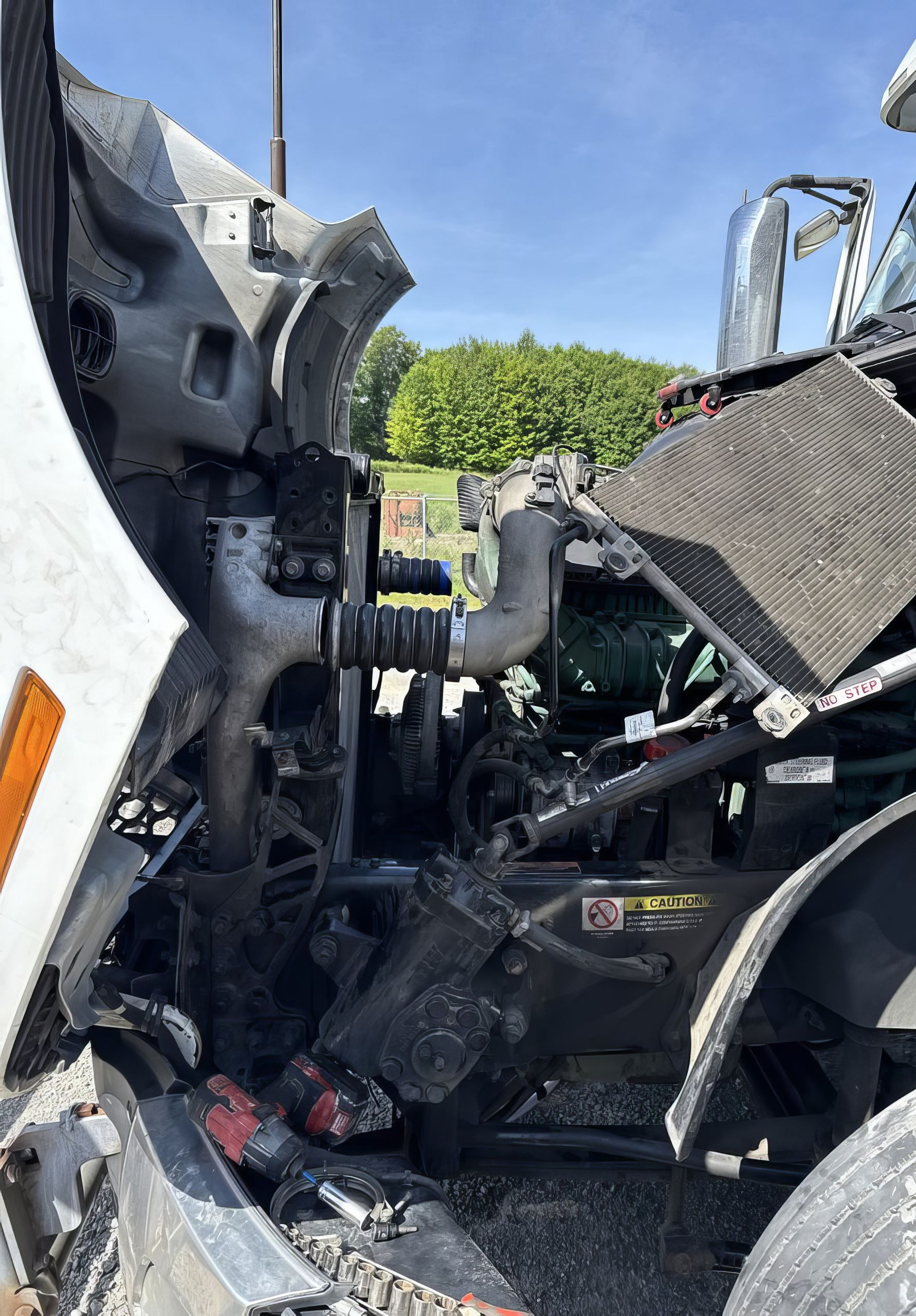 Severe truck cab wreckage with crushed metal and exposed engine parts beside a road