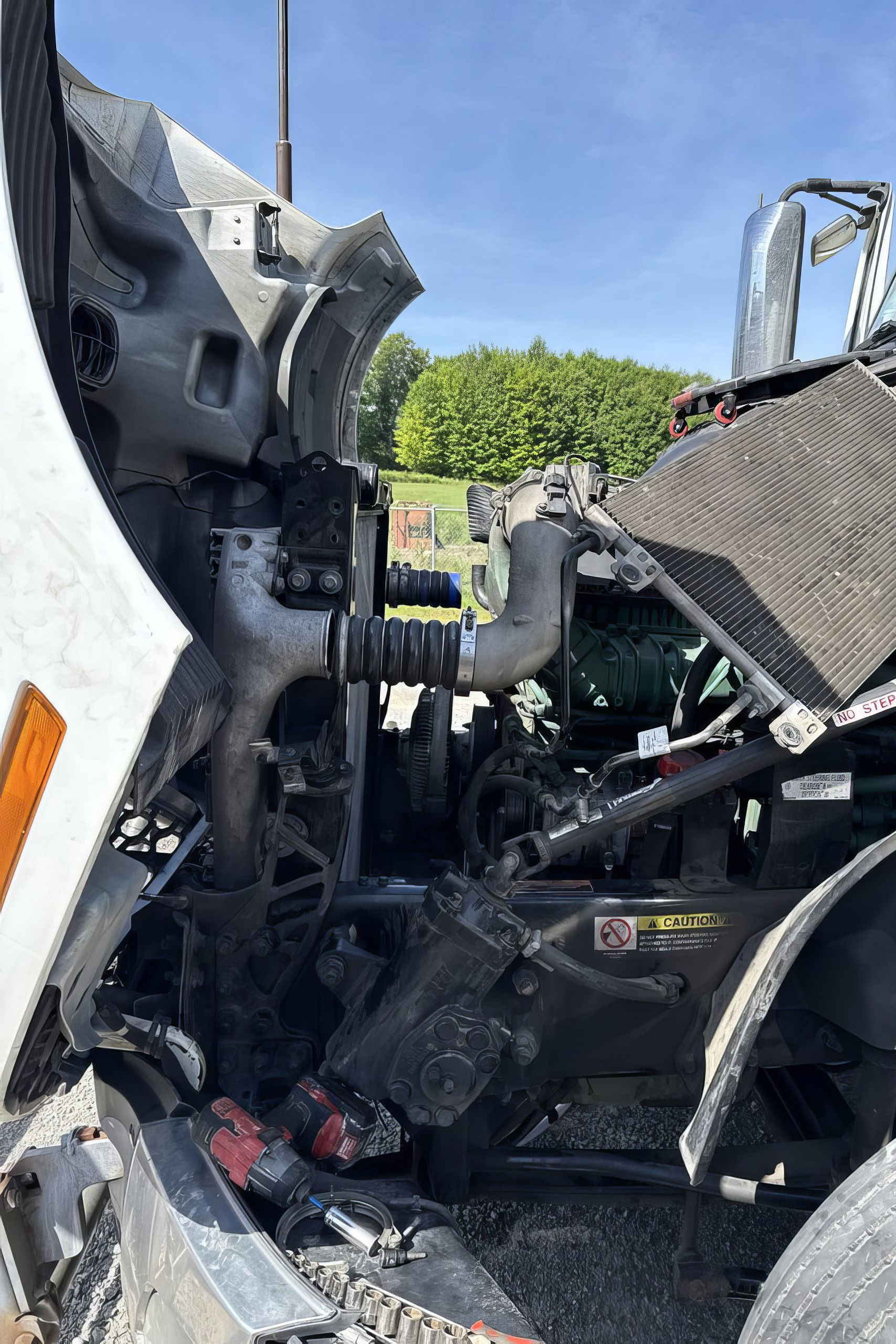 Severe truck cab wreckage with crushed metal and exposed engine parts beside a road