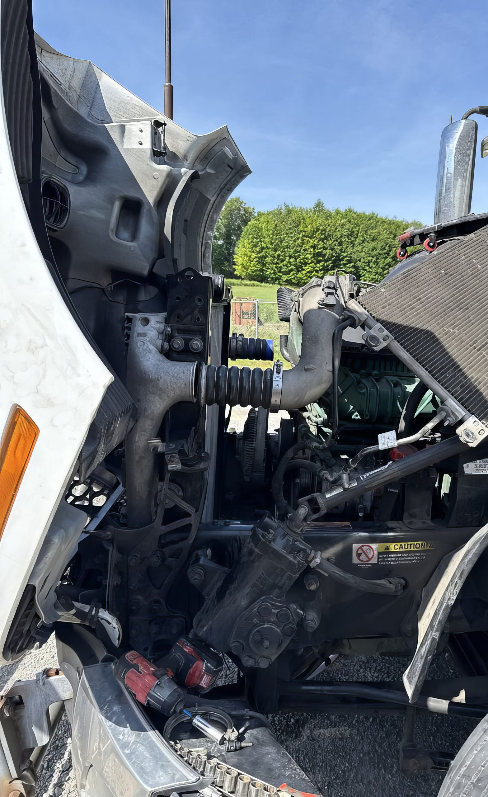 Severe truck cab wreckage with crushed metal and exposed engine parts beside a road