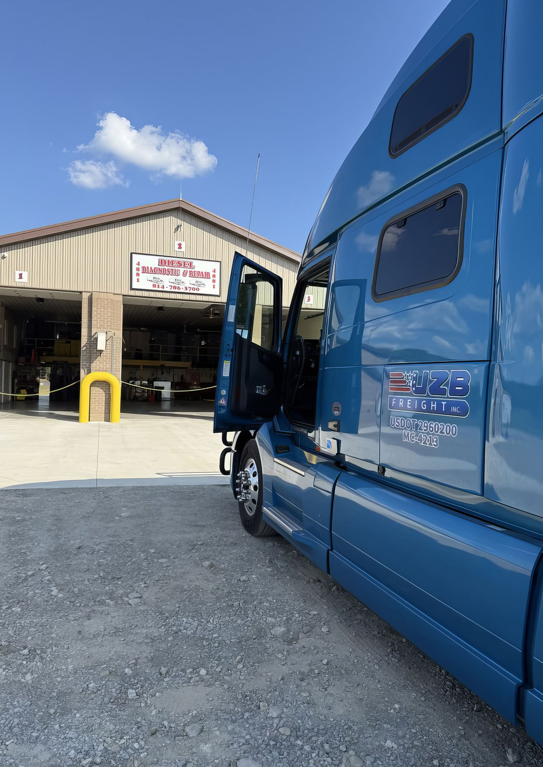 Blue semi-truck parked outside a warehouse loading dock under a clear sky