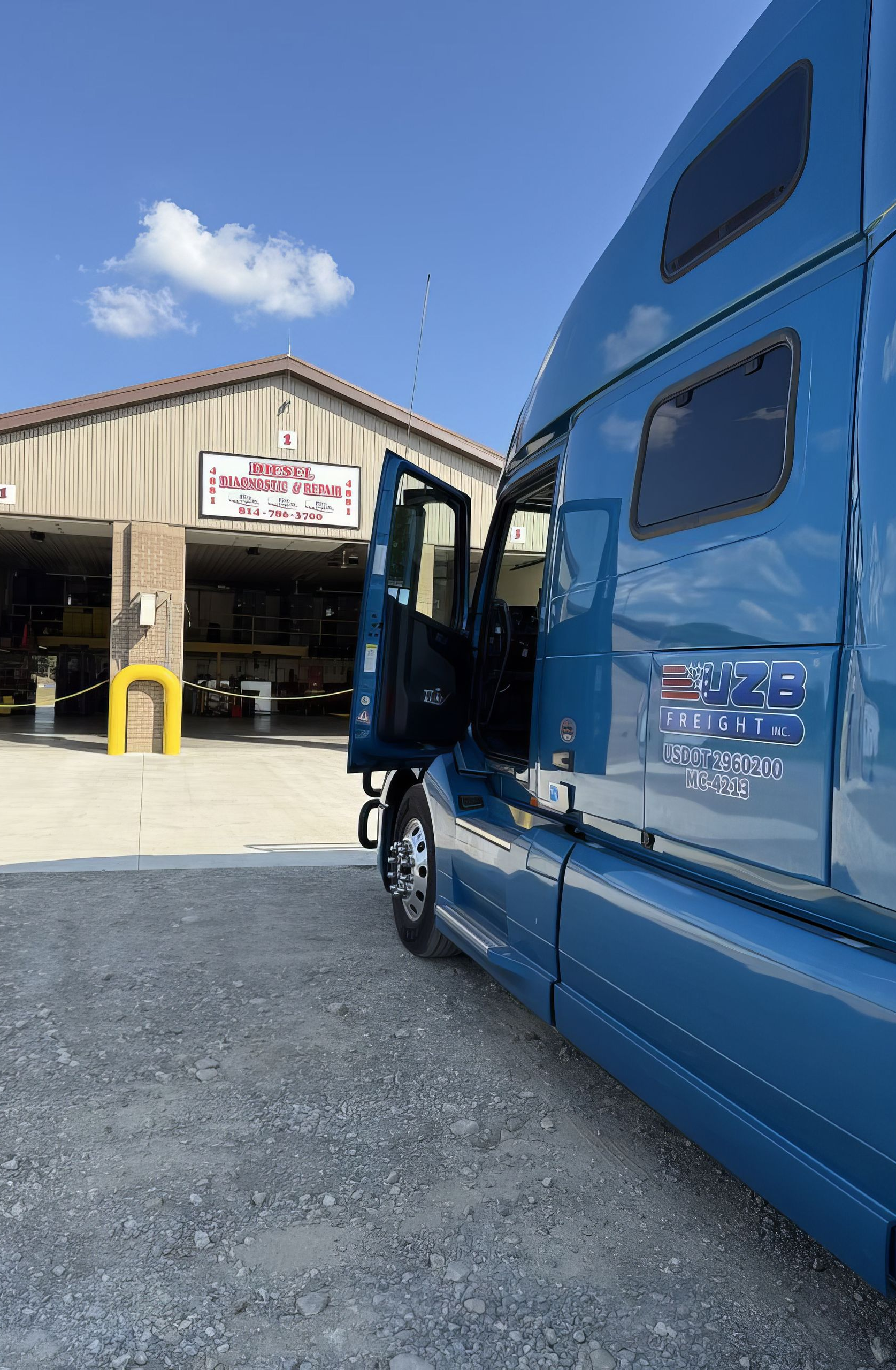 Blue semi-truck parked outside a warehouse loading dock under a clear sky
