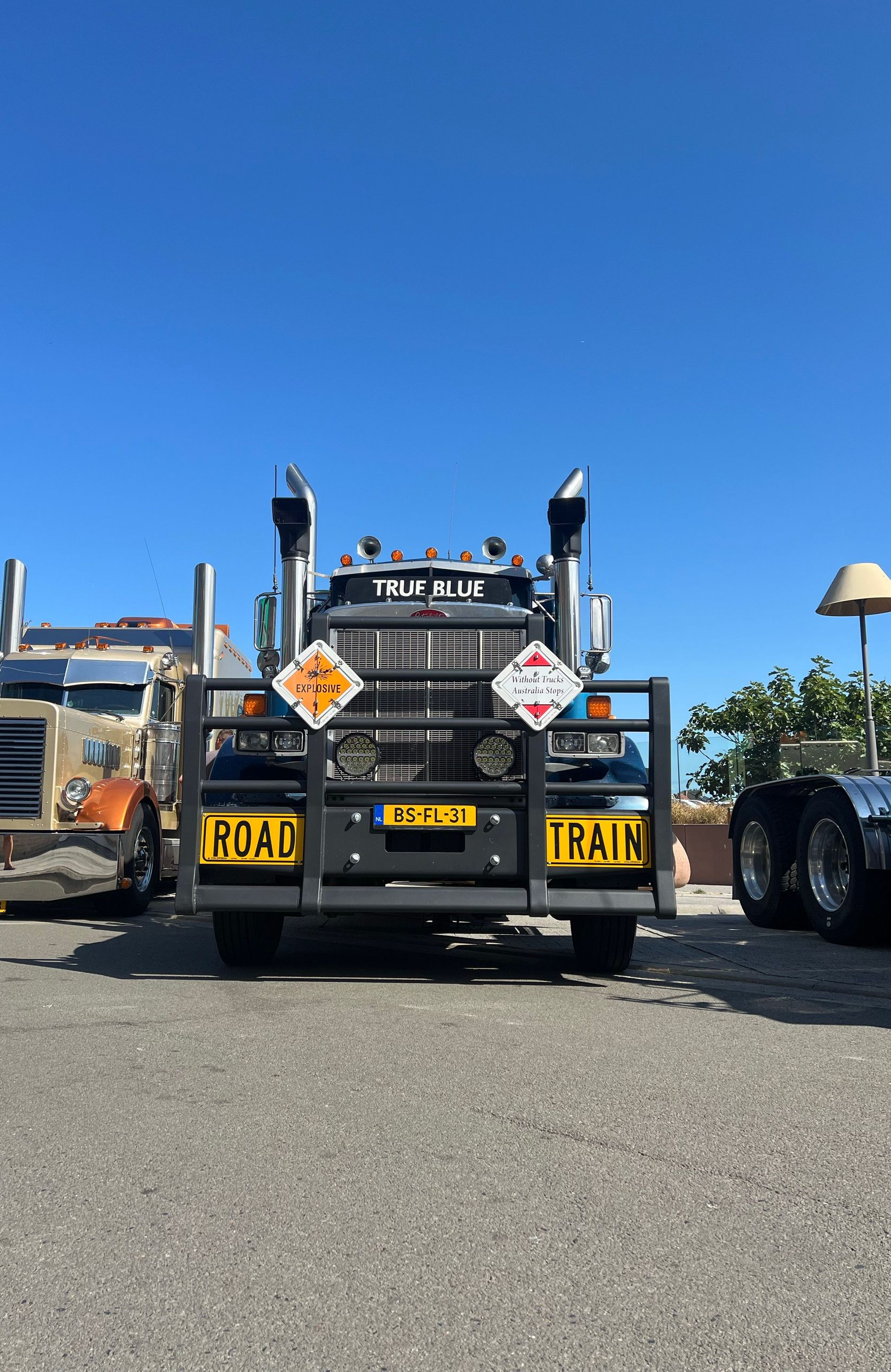 Rear view of a black tow truck with yellow accents parked on a gravel lot under a clear blue sky