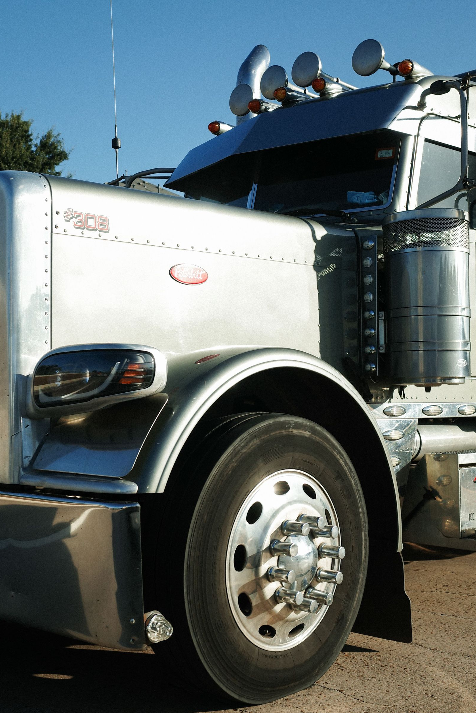 Chrome semi-truck cab with chrome grille and wheels parked outdoors under a blue sky