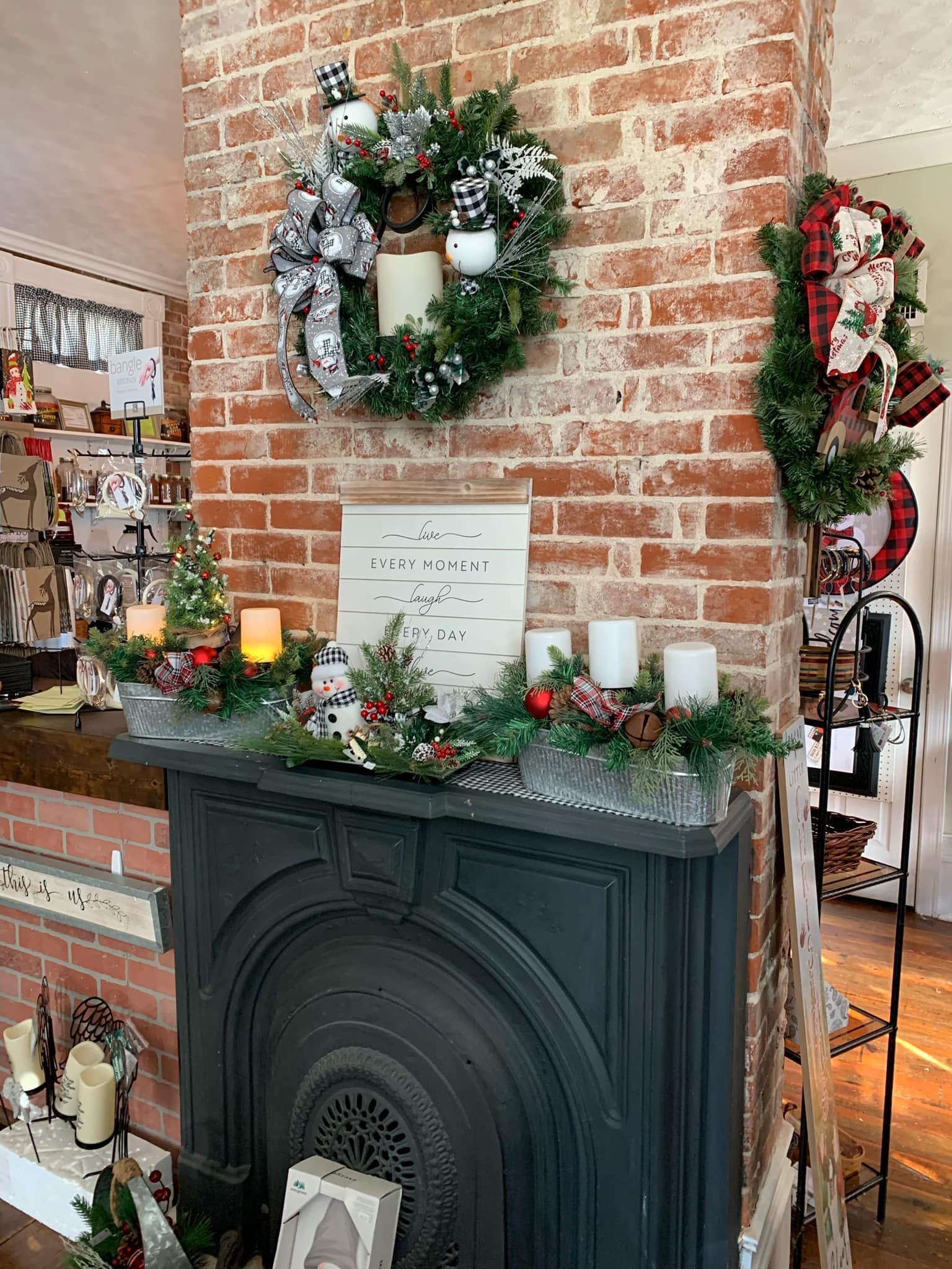 A fireplace decorated for christmas with a wreath and candles on it.