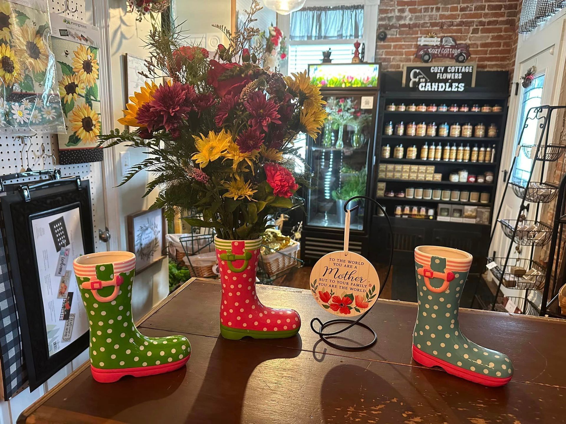 A table with three polka dot rain boots and a vase of flowers on it.