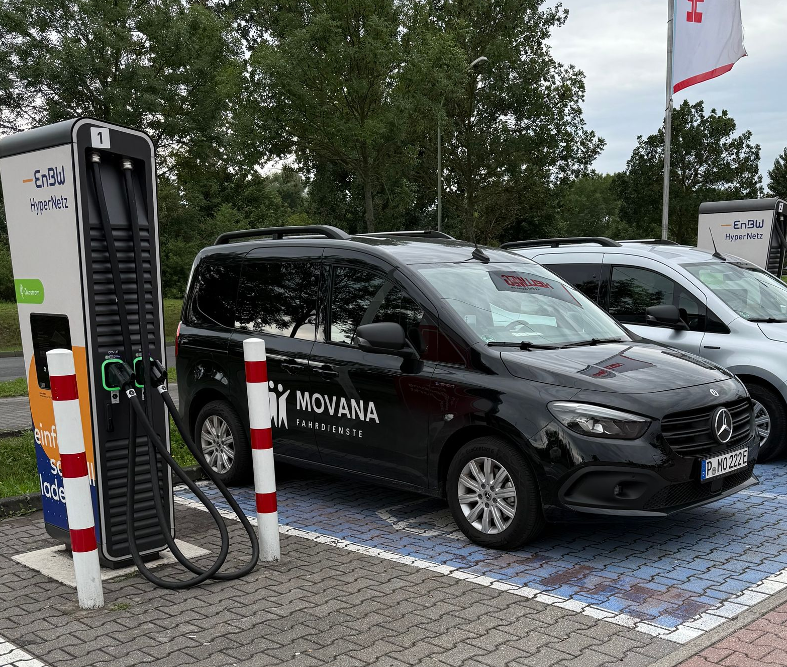 Rückseite eines weißen Movana Fahrdienst-Sprinters mit grünen Akzenten und Rollstuhlzugänglichkeitssymbol neben einem Feld.
