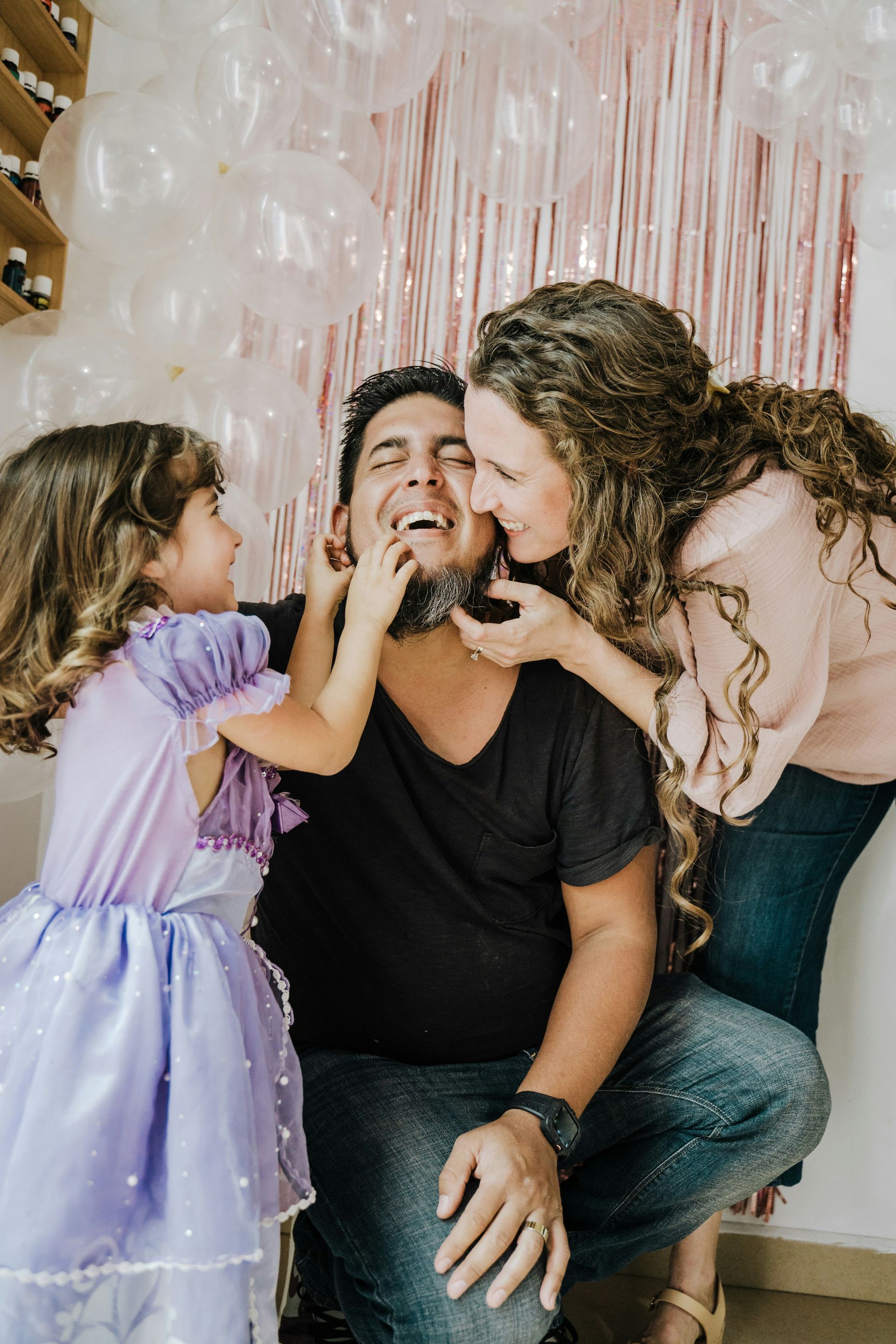 A man and two little girls are playing with a man 's beard.