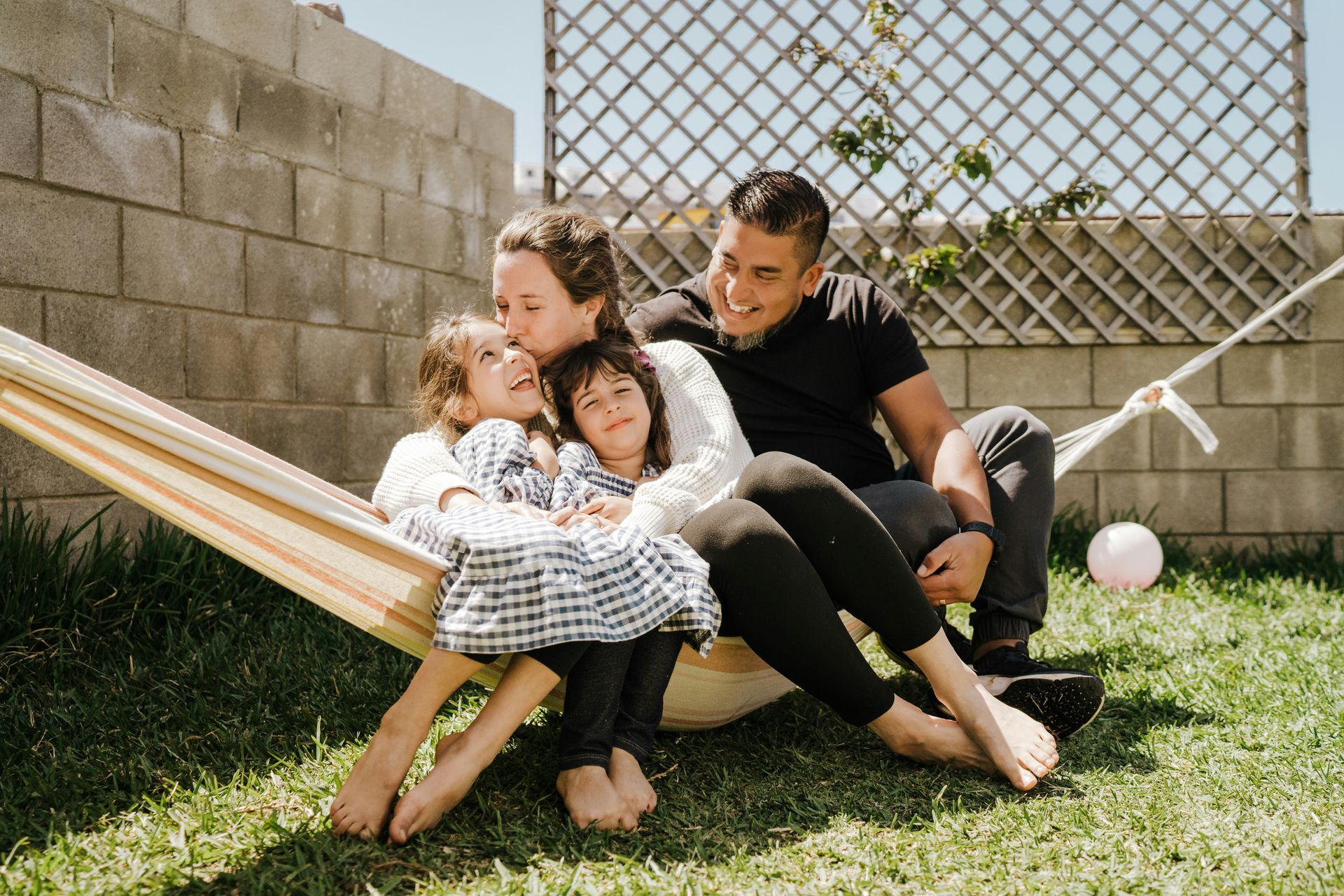 A family is sitting in a hammock in the grass.