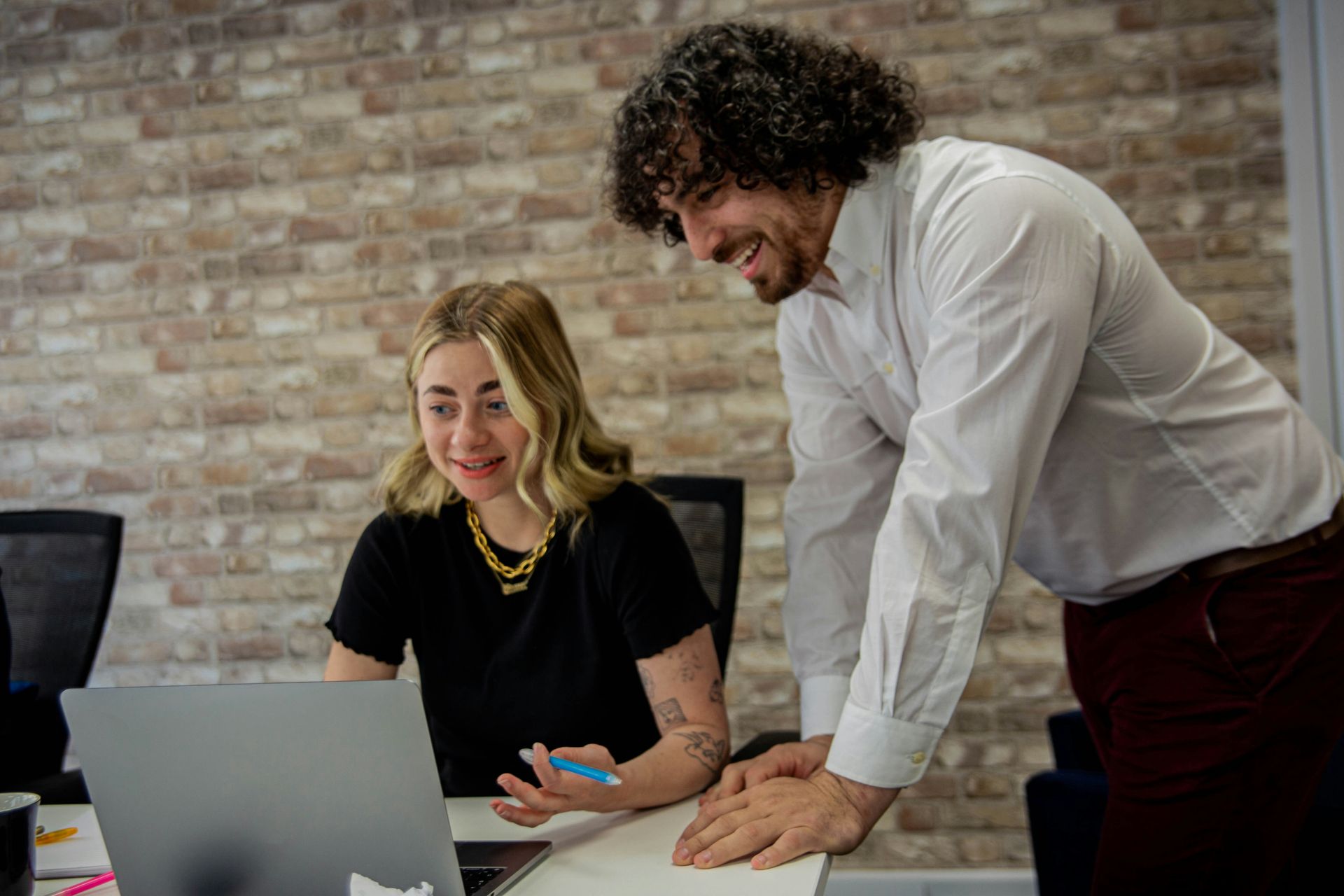 A man and a woman are looking at a laptop computer.