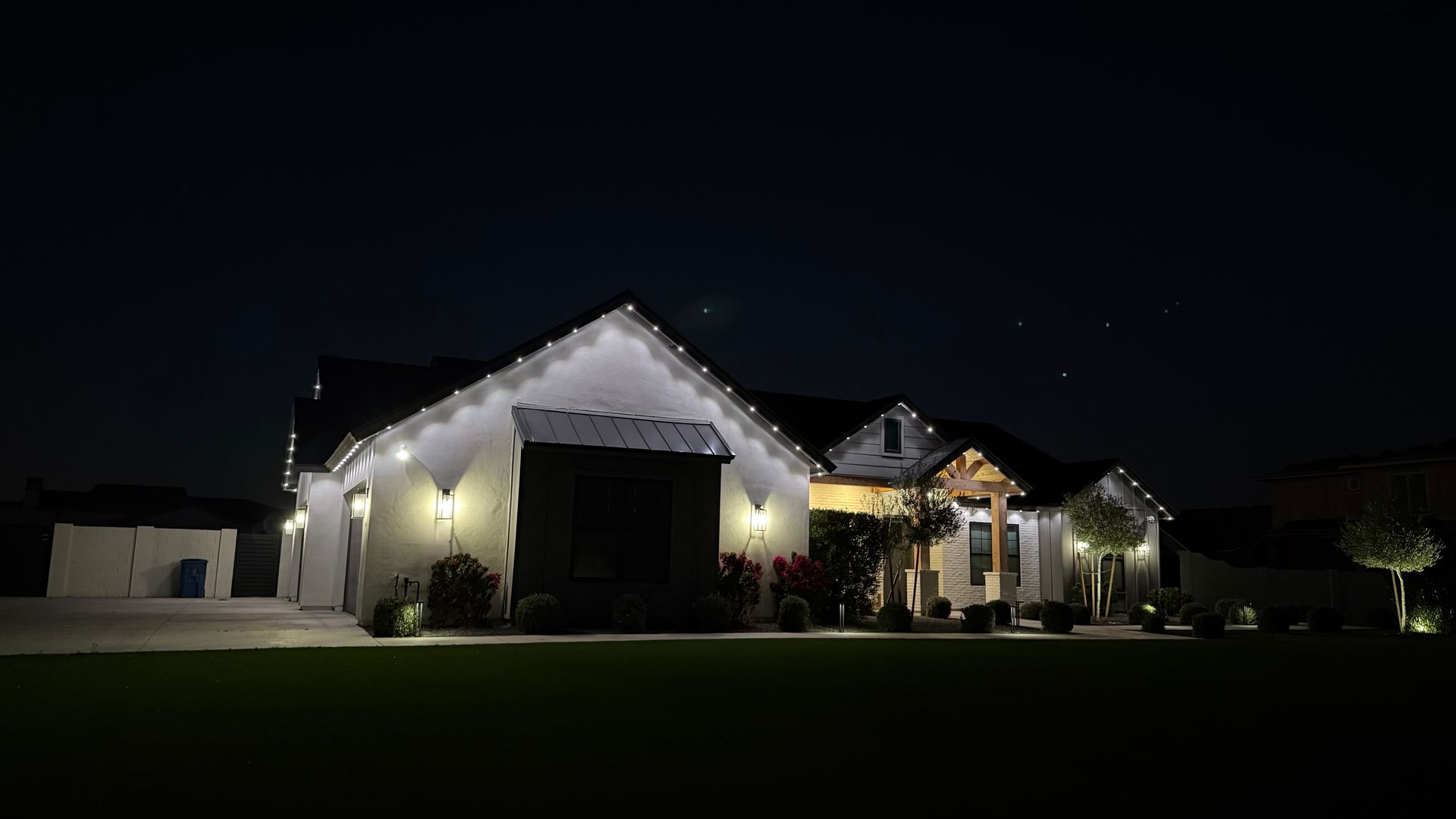 Illuminated suburban house at night with white lights along the roofline and front entrance