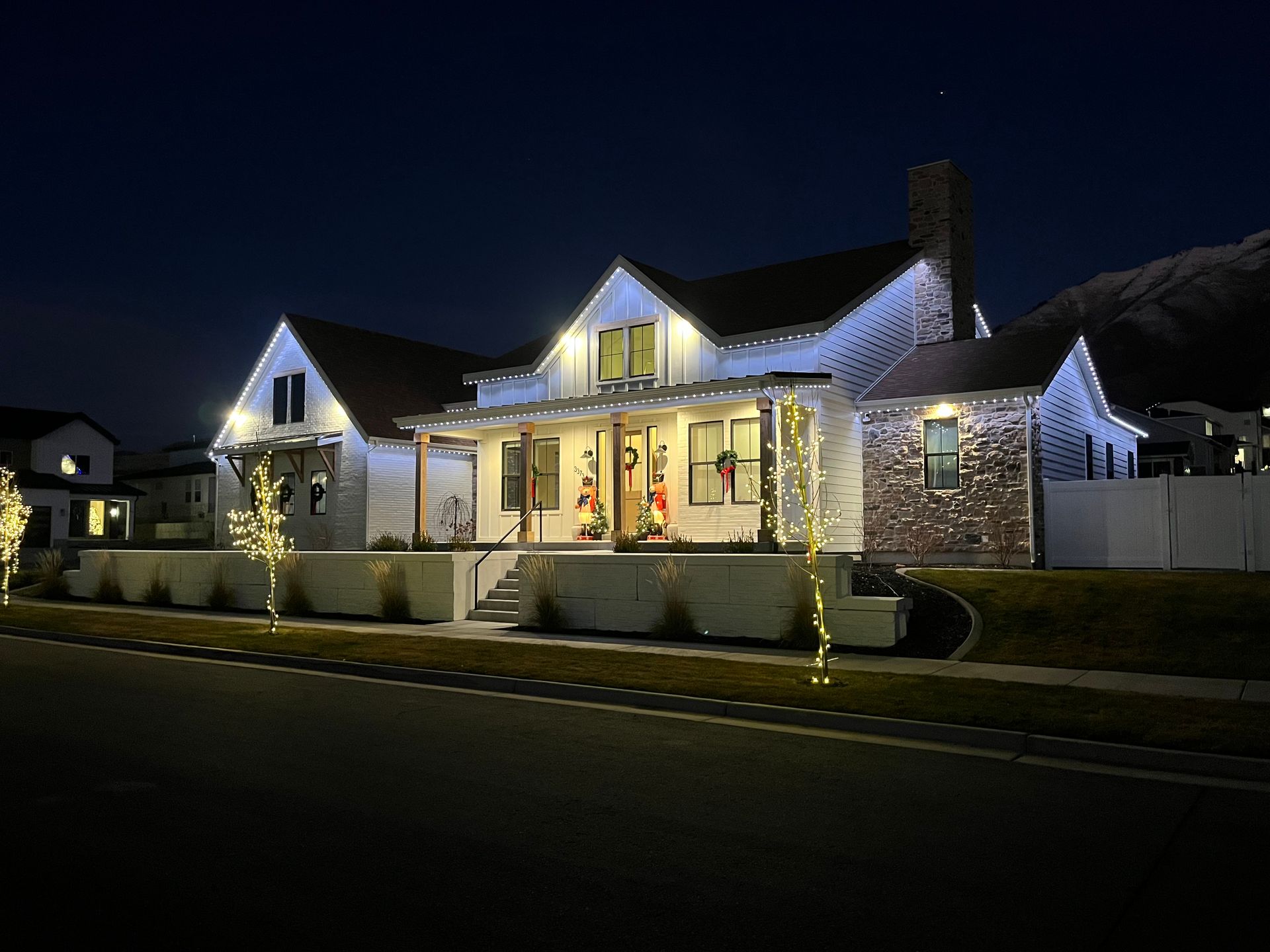 Lit house decorated with white lights at night on a suburban street
