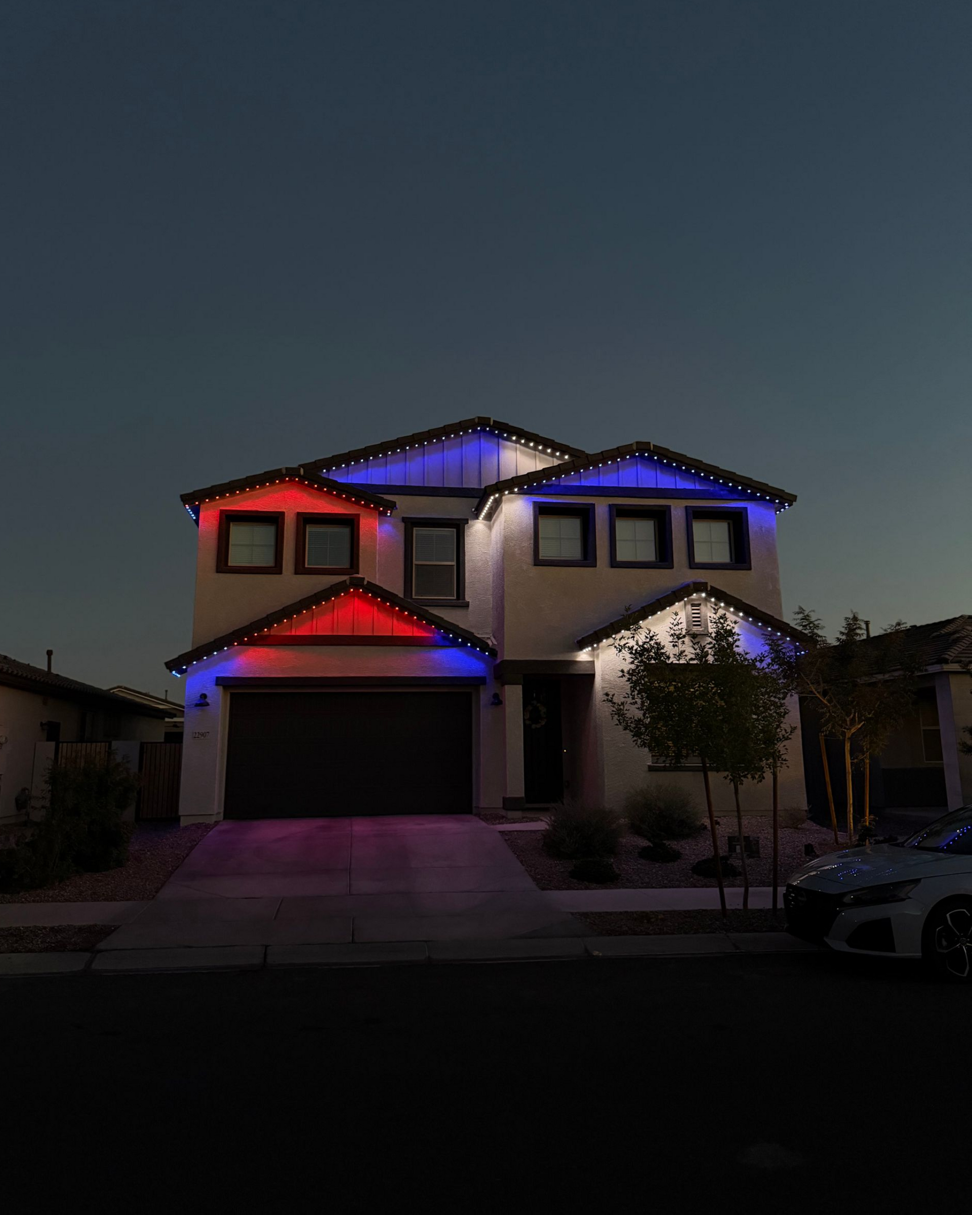 Two-story suburban house at dusk with blue and red roof lights illuminated