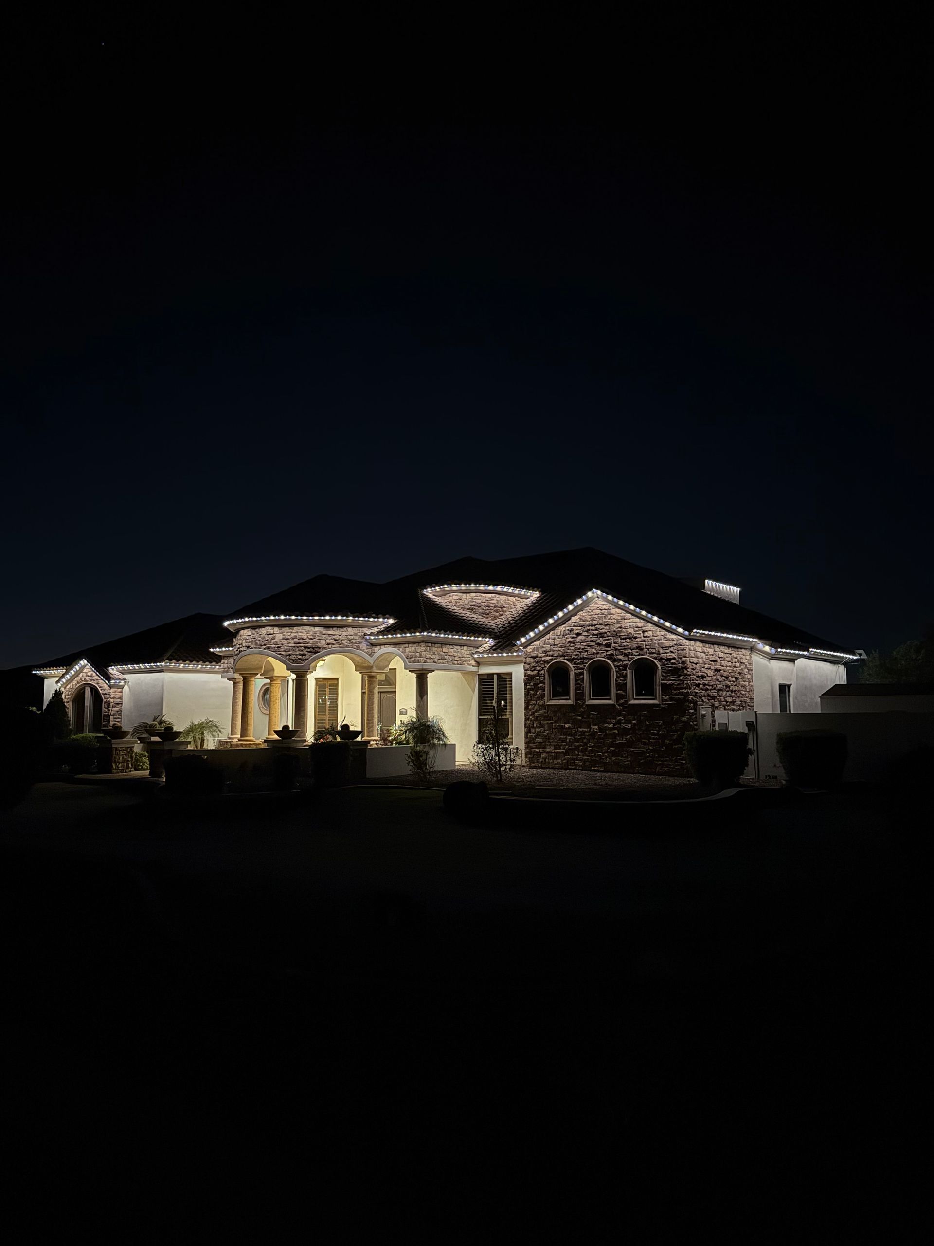 Single-story house warmly lit at night under a dark sky