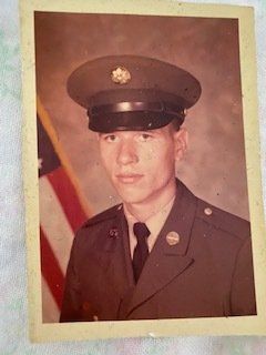 A man in a military uniform is standing in front of an american flag.