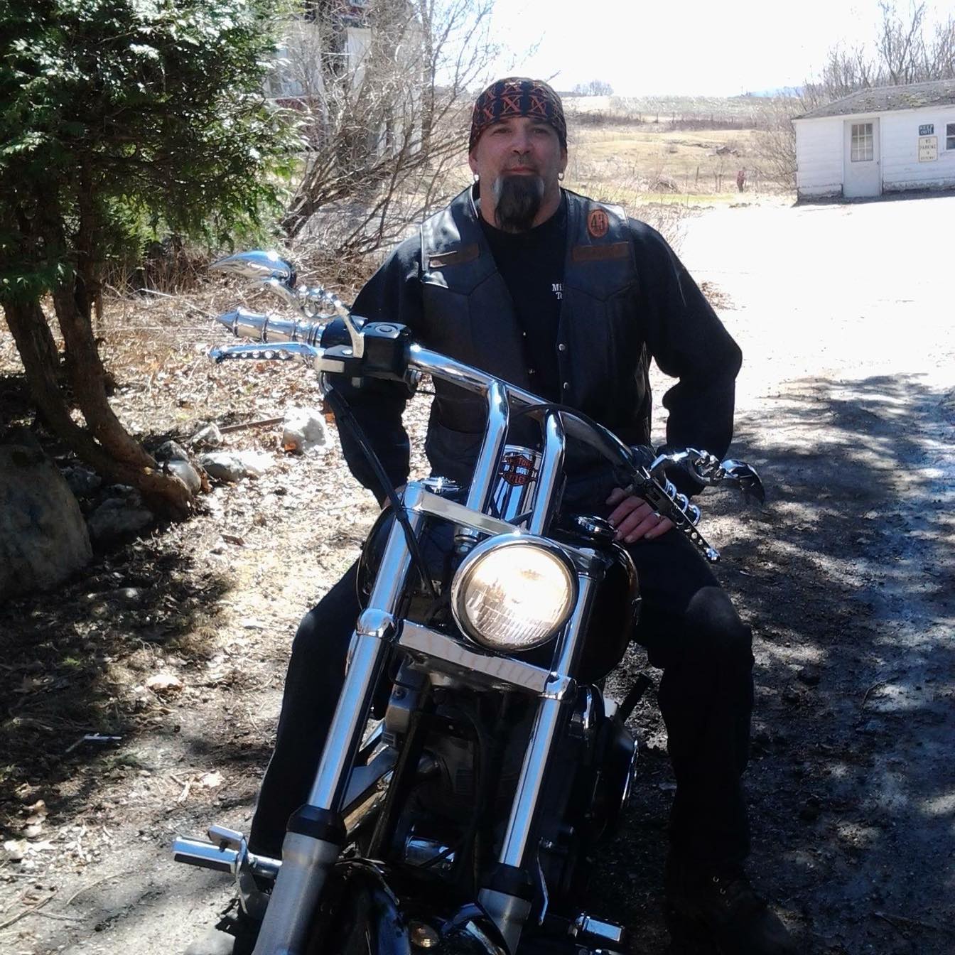 A man in a black vest is sitting on a motorcycle