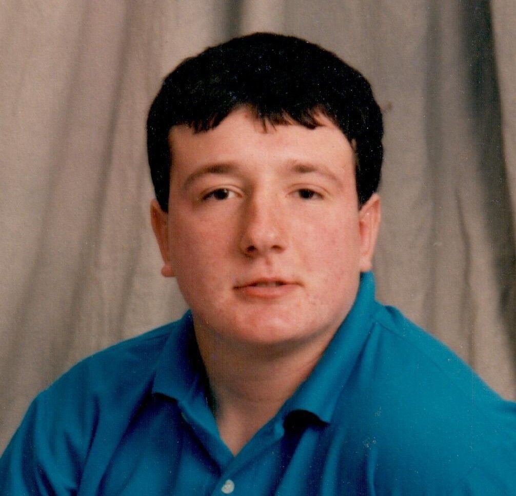 Studio portrait of a person in a blue shirt against a gray backdrop
